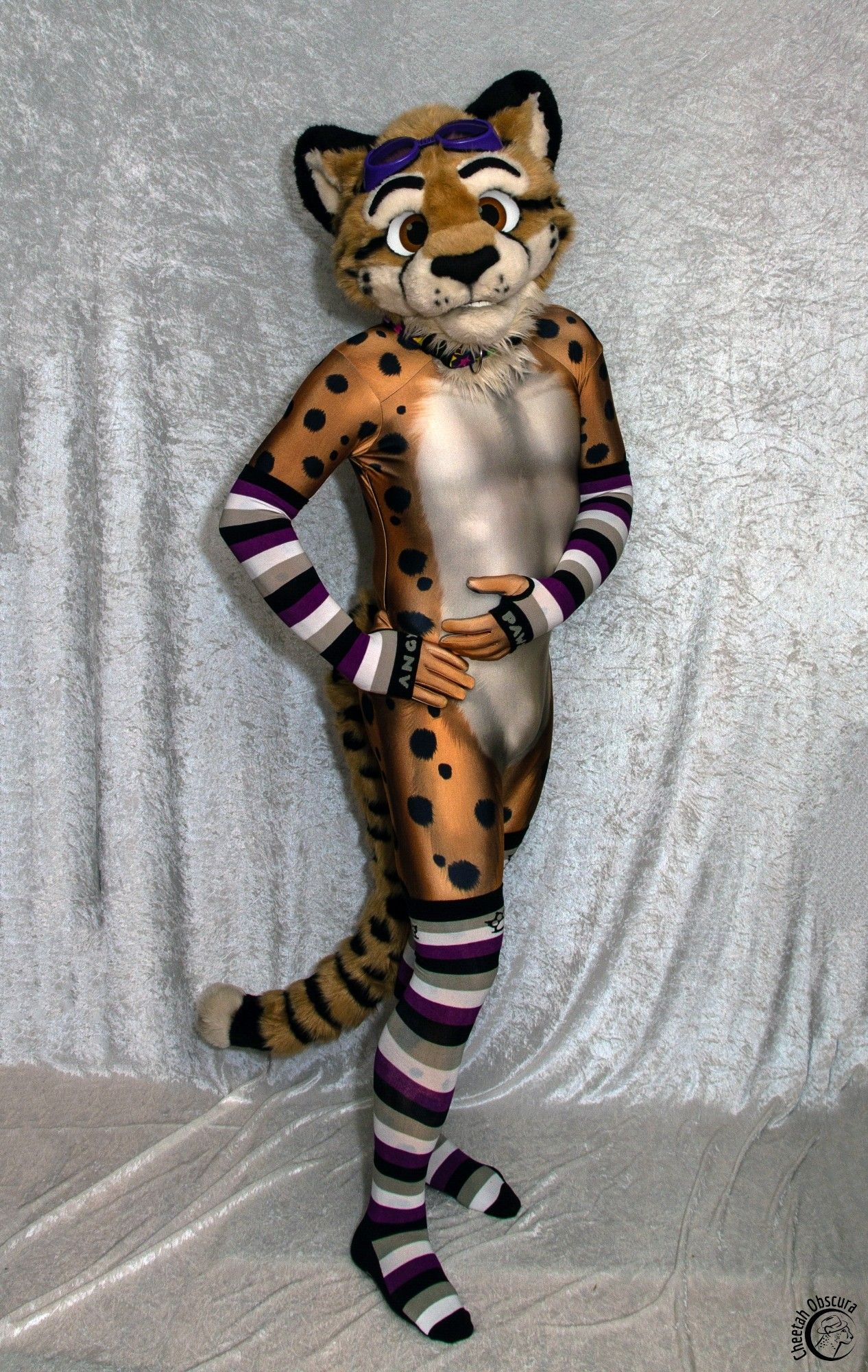 Photo of Obscura in fursuit partial, spandex petsuit, and asexual color socks and arm warmers