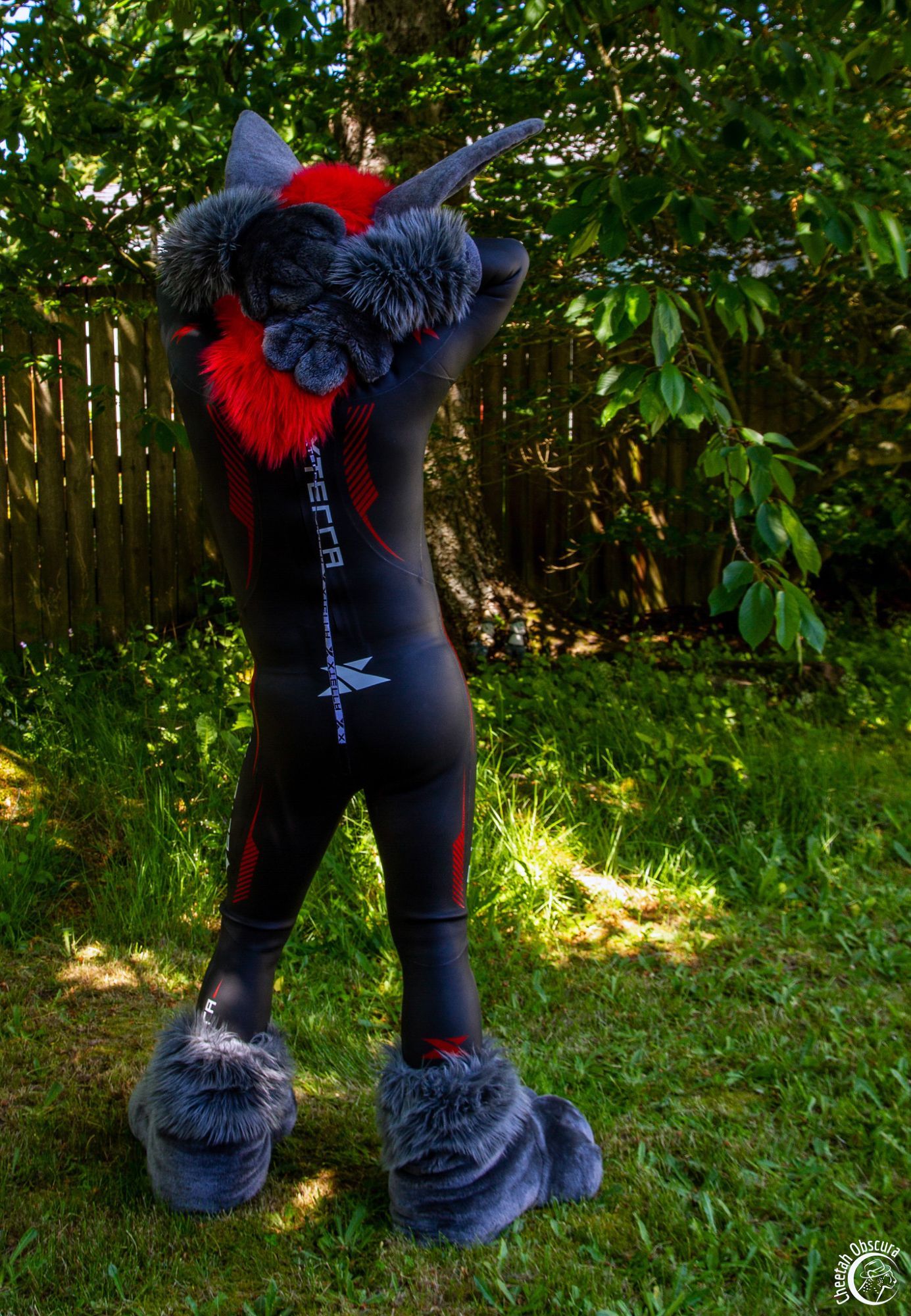 Photo of Kofi bat in fursuit partial and wearing a red and black Xterra wetsuit - back view