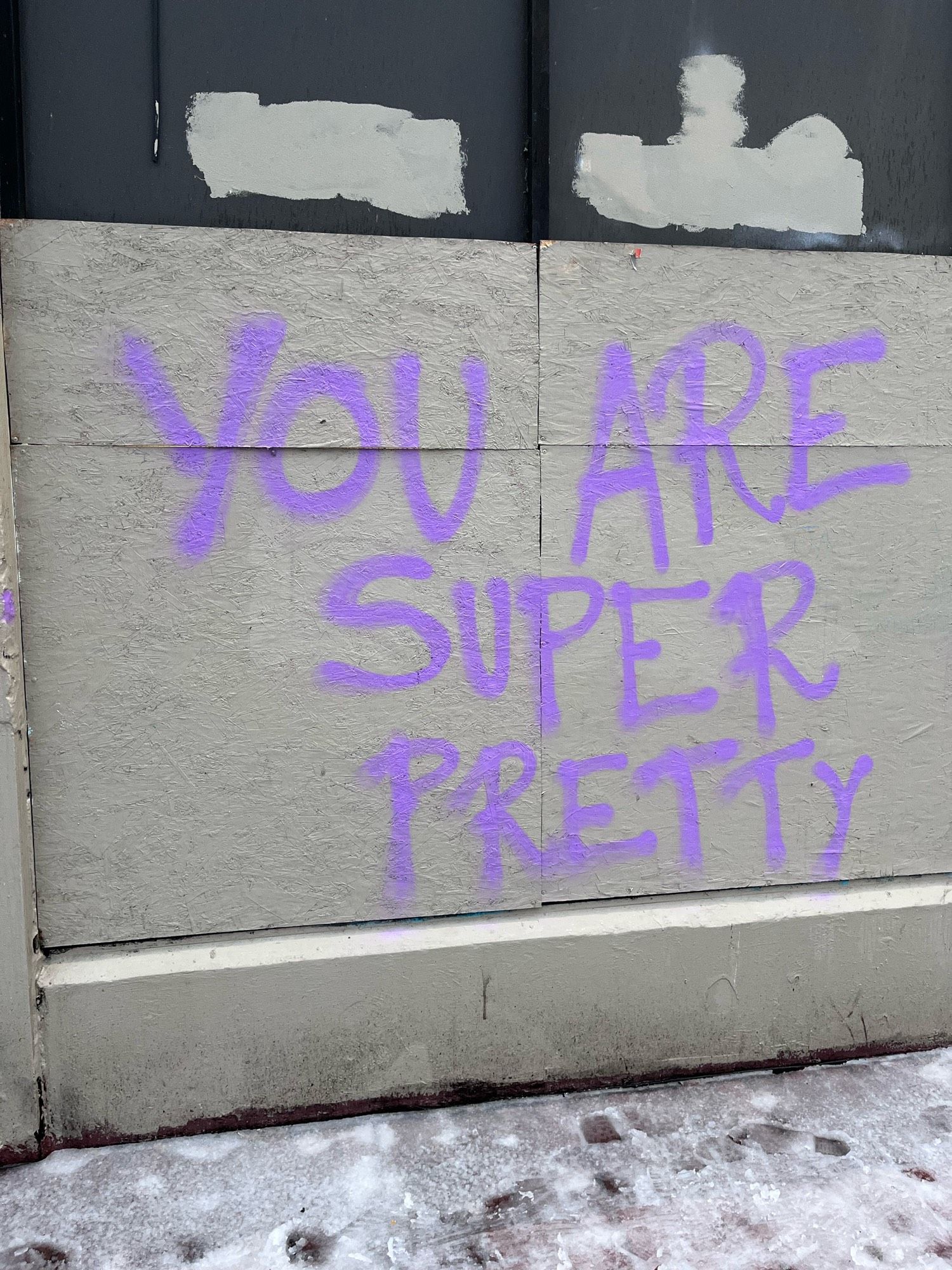 a graffitied concrete wall in Portland, Oregon with the words “YOU ARE SUPER PRETTY” spray painted in purple. photographed by me on December 24, 2022