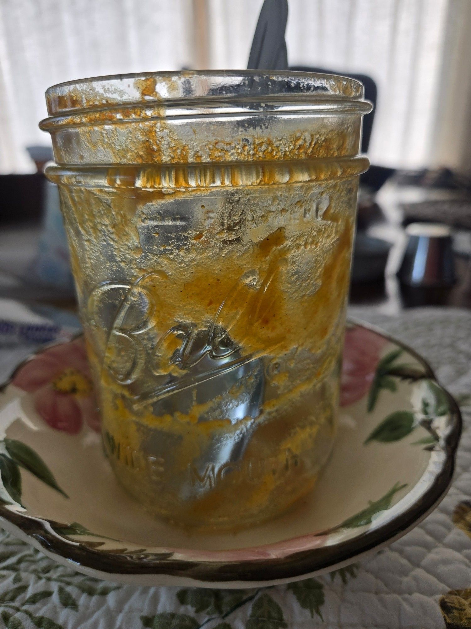 A Photo of a Ball pint size canning jar, with a soup spoon inside. It did have Autumn Soup in it...but I ate it. The jar is sitting inside a small Desert Rose dessert bowl, on top of a quilted placemat. On the diningroom table. Curtains are drawn, because it's hot outside.