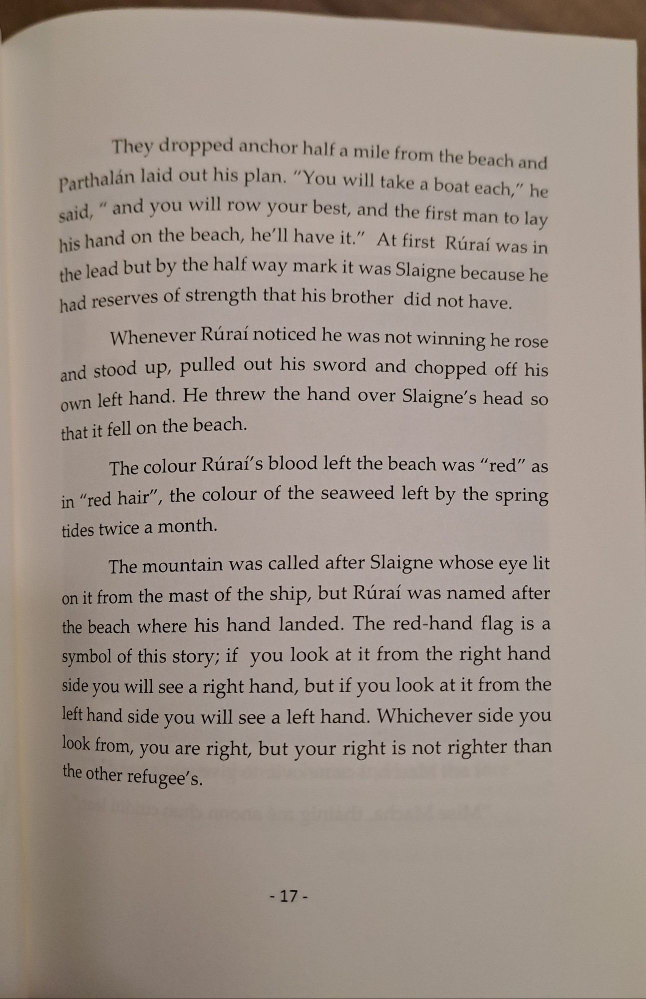 Story of the 'red hand' legend of the first people to arrive in Ulster, Ireland. The text reads" Rúraí pulled out his sword and chopped off his own left hand. He threw the hand over Slaigne's head so that it fell on the beach. The colour Rúraí's blood left the beach was "red" as in "red hair", the colour of the seaweed left by the spring tides twice a month. The mountain was called after Slaigne whose eye lit on it from the mast of the ship, but Rúraí was named after the beach where his hand landed. The red-hand flag is a symbol of this story; if you look at it from the right hand side you will see a right hand, but if you look at it from the left hand side you will see a left hand. Whichever side you look from, you are right, but your right is not righter than the other refugee's."