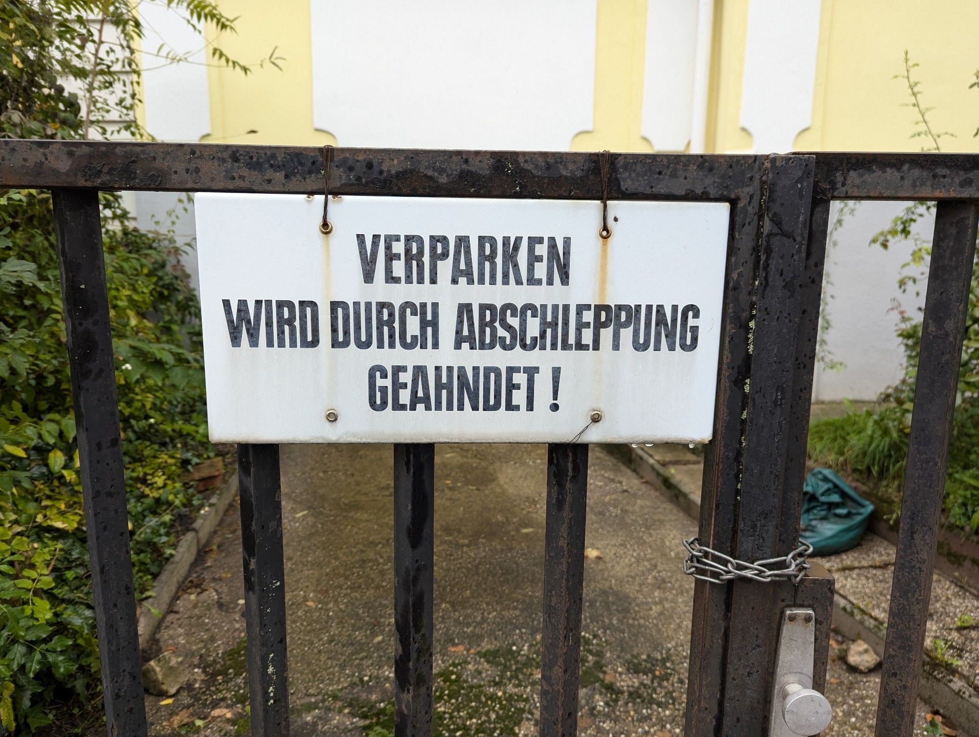 Ein Blechschild an einer Einfahrt mit der Aufschrift "VERPARKEN WIRD DURCH ABSCHLEPPUNG GEAHNDET!"