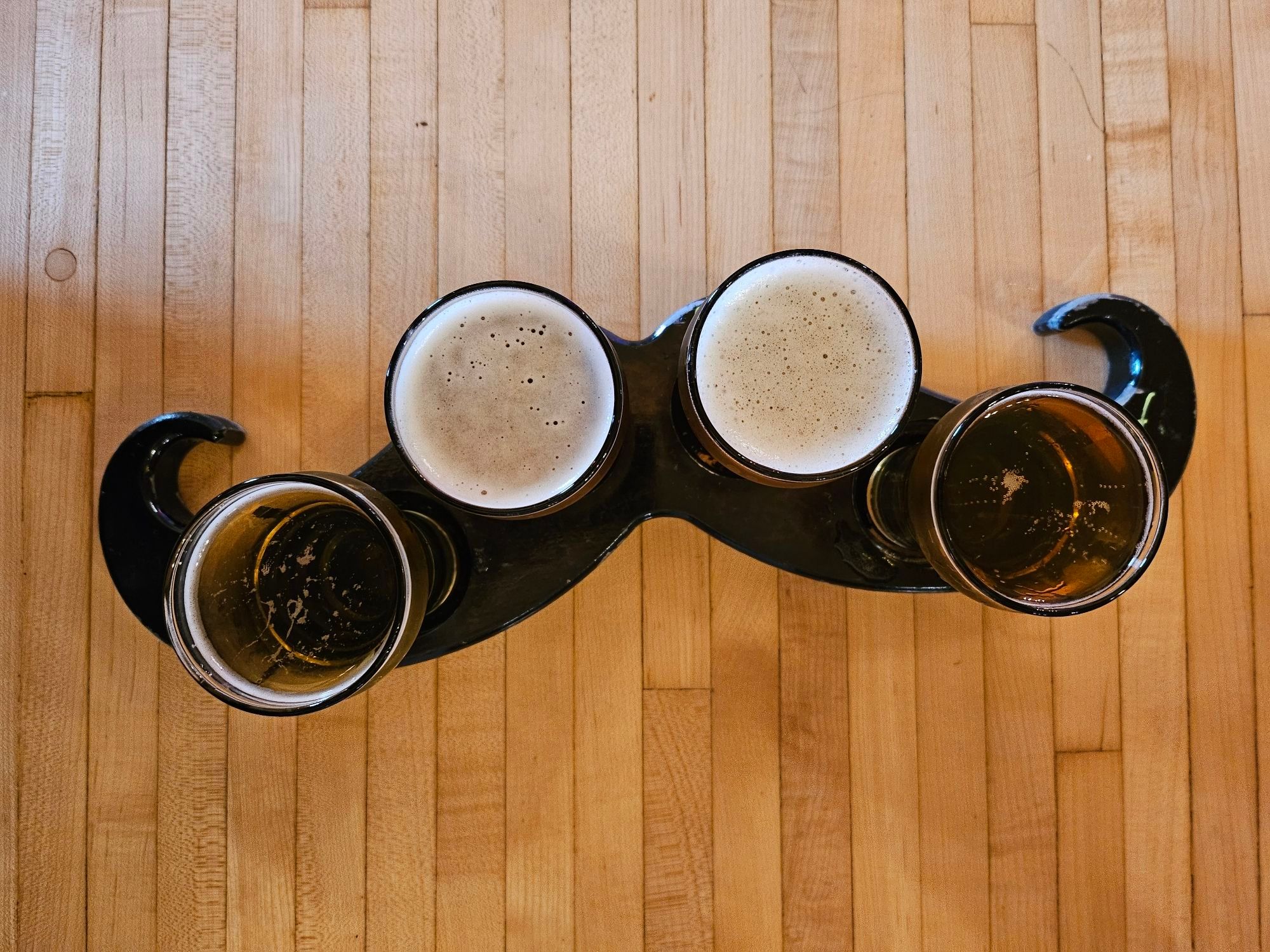 a flight of four beers in a tray shaped like a mustache