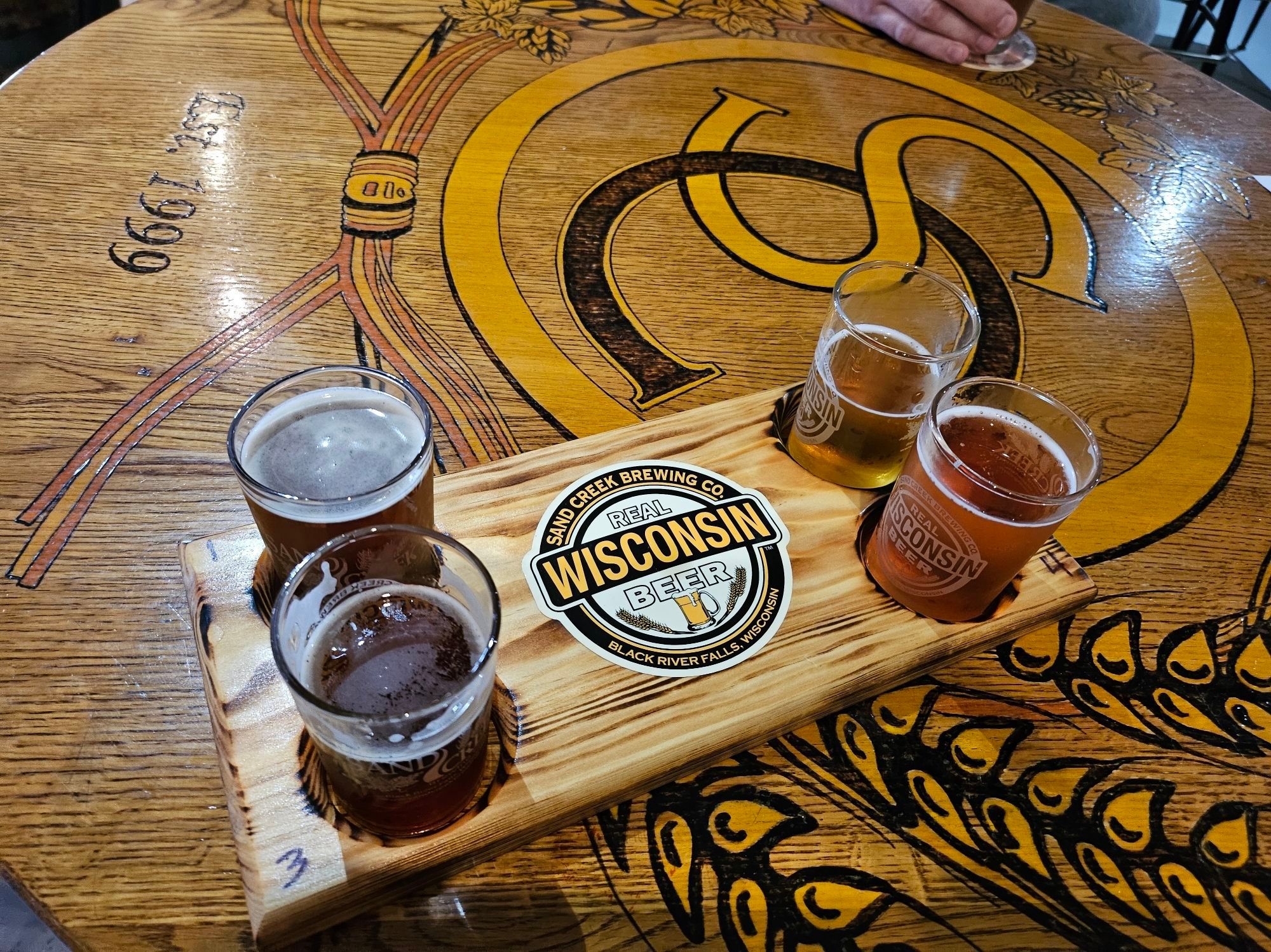 a flight of four beers on a tray that says WISCONSIN real big