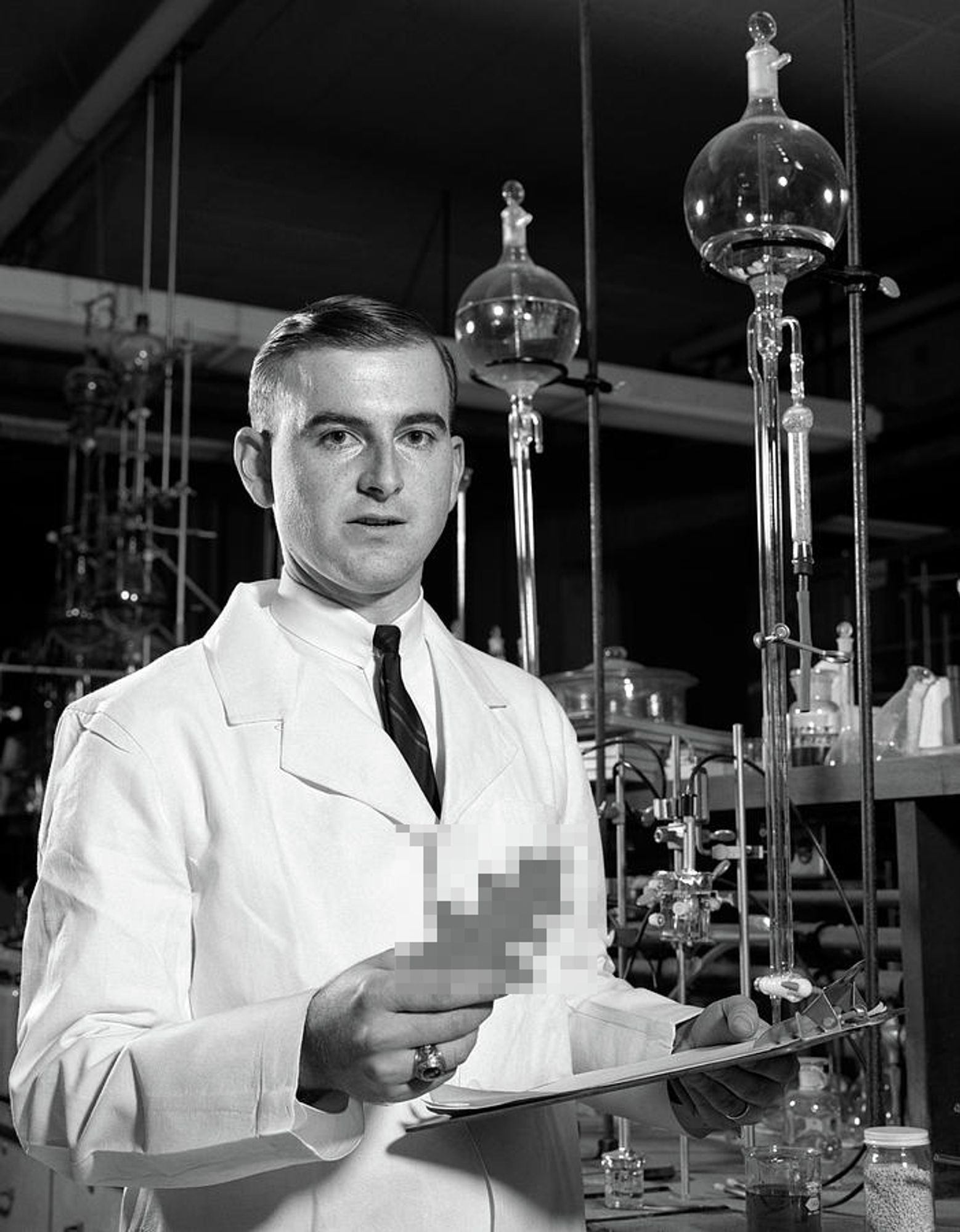 Photo of a scientist holding something that has been blured/pixelated out.