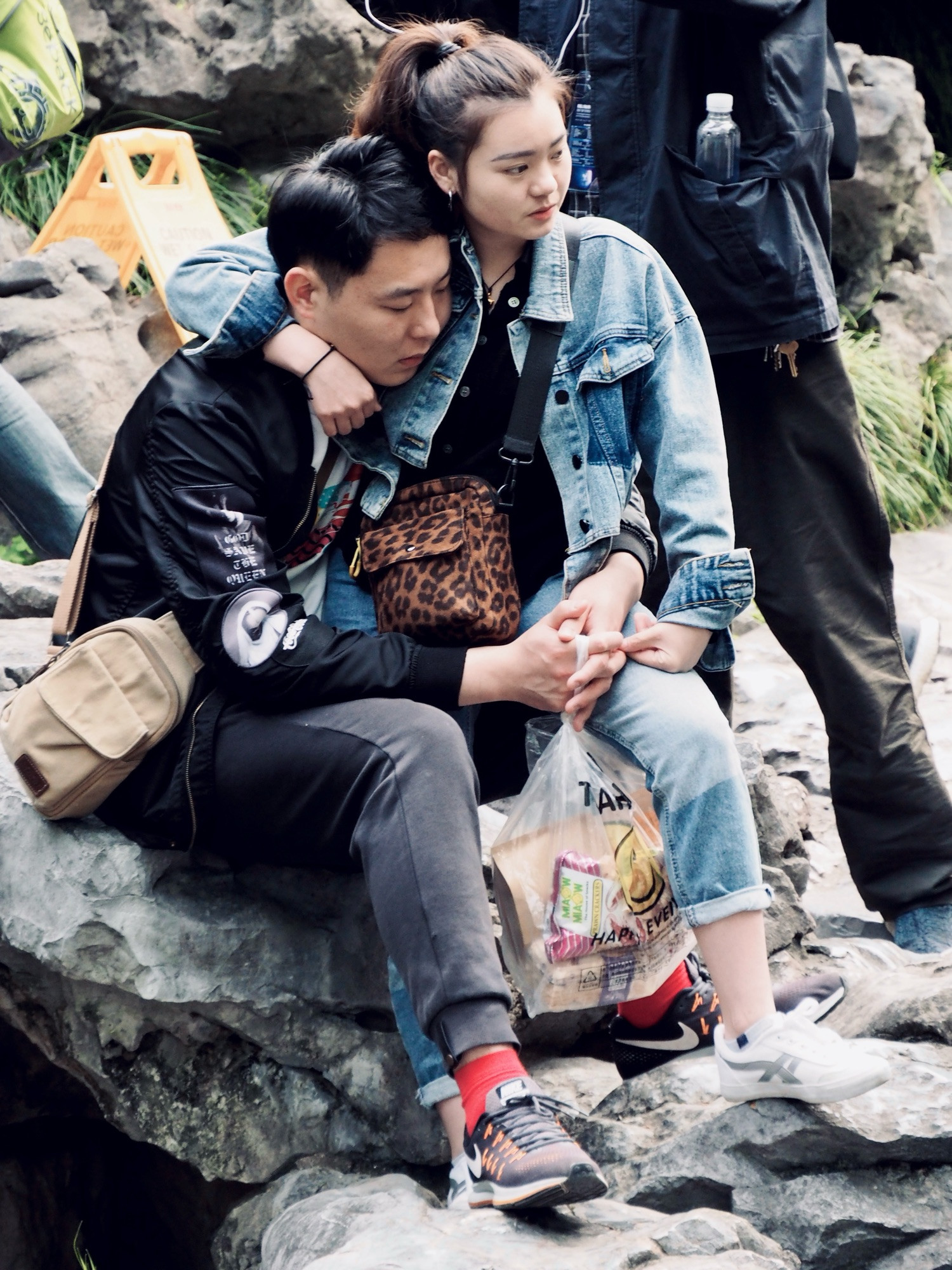 A couple sitting on a rock embrace themselves on a park in Shanghai