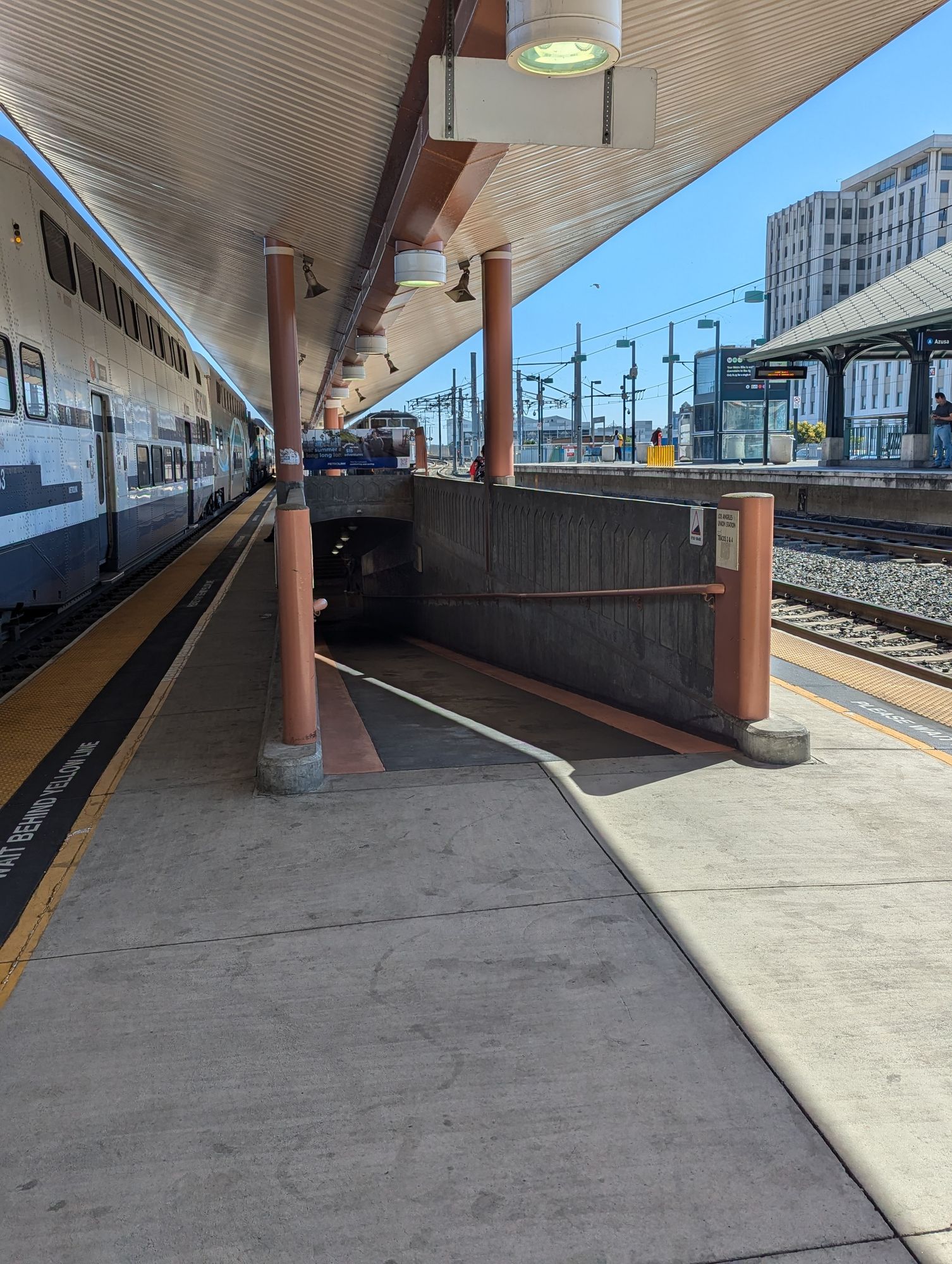 Train platform with tracks on the right and left. In the middle of the platform is a large pedestrian ramp leading downwards.