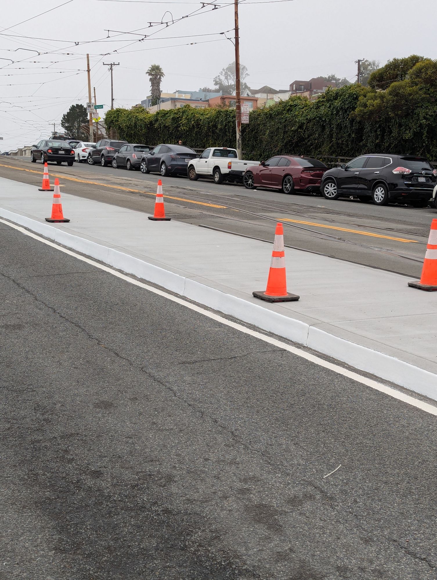 Light rail boarding island with traffic cones placed along both edges and white paint on the edge of the platform.