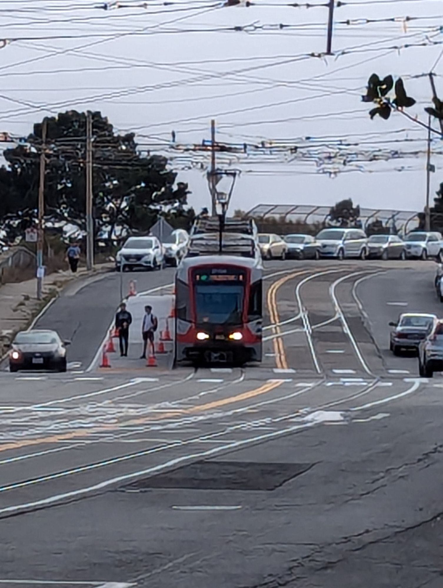 A light rail vehicle next to a low floor platform. There are several people on the platform.