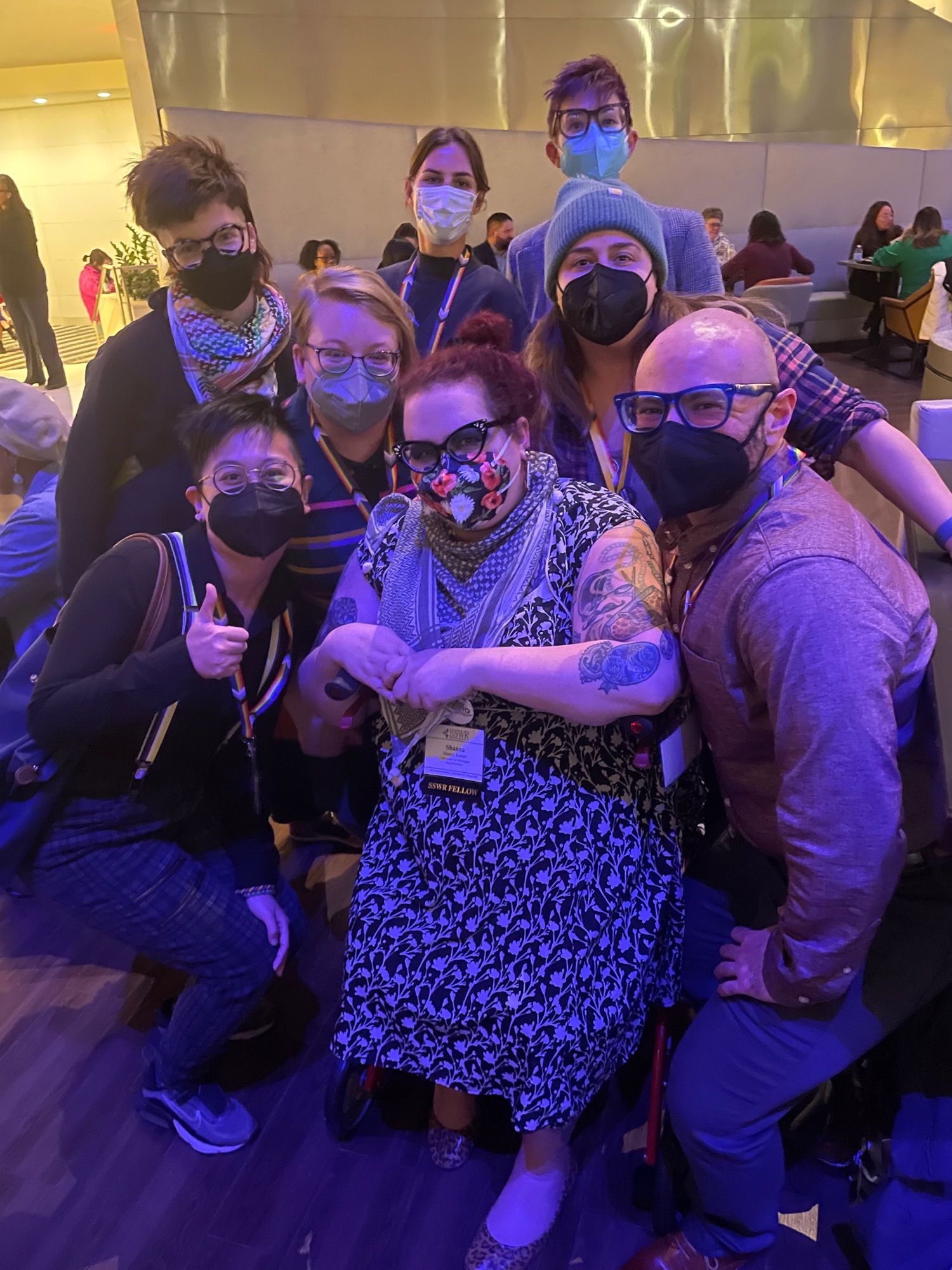 Group of masked folks posing in a hotel bar