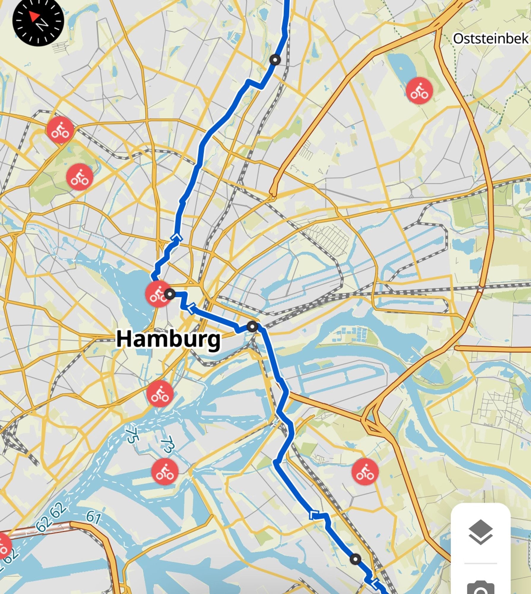 Das Bild zeigt eine Karte von Hamburg und Umgebung. Auf der Karte ist eine blaue Linie eingezeichnet, die eine Route darstellt. Diese Route verläuft von Norden nach Süden durch Hamburg. Es gibt mehrere Symbole mit einem roten Hintergrund und einem weißen Fahrradsymbol darauf, die auf der Karte verteilt sind. Diese Symbole könnten Fahrradstationen oder -verleihstellen darstellen. Im oberen rechten Bereich der Karte ist der Ort "Oststeinbek" beschriftet. Die Karte zeigt auch Straßen, Wasserwege und andere geografische Merkmale der Region.