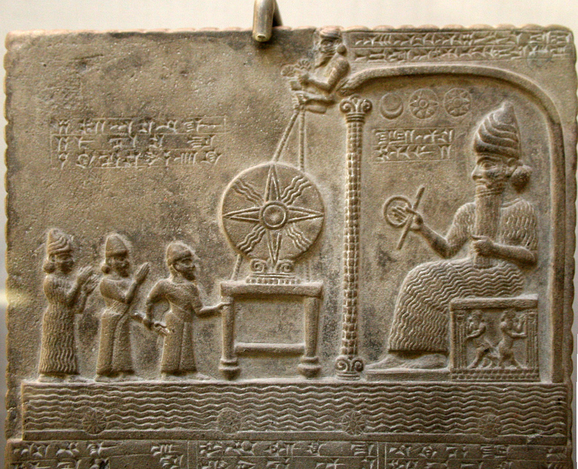 Detail from the Tablet of Shamash, from ca. 888-855 BCE. It is a stone relief in Assyrian style with cuneiform writing on it. On the right is a male figure seated on a throne, probably the sun god Shamash. On the left is a group of three standing figures, perhaps worshippers. In the middle between them is the sun disc (a circle with a four-pointed star and four rays) above a table or altar.