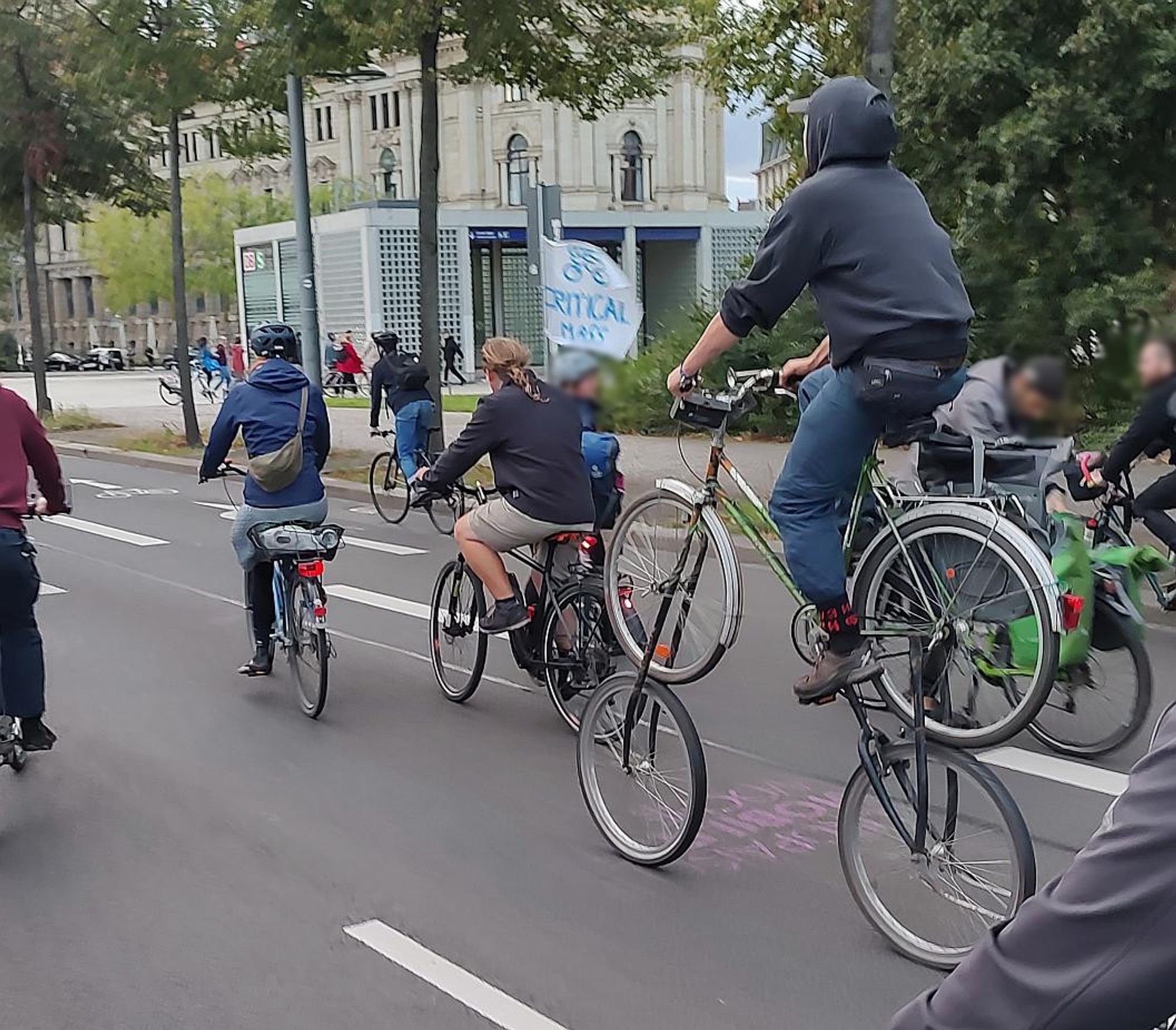 Mehrere Fahrräder auf einer Straße - eines mit "Critical Mass"-Fahne, ein selbstgebautes mit 2x2 Rädern übereinander.