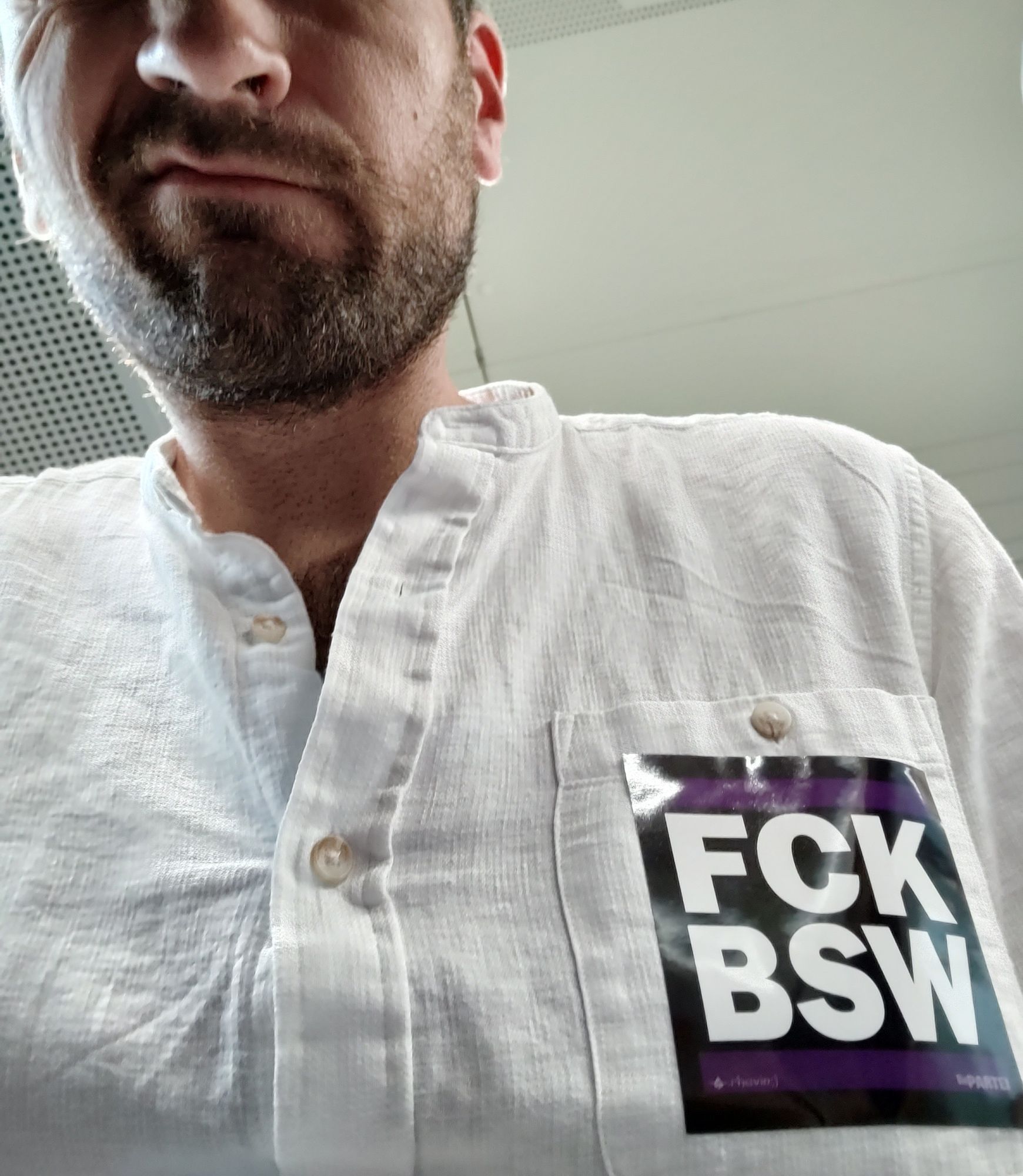 Ein verzogenes Gesicht, darunter ein Hemd mit einem Aufkleber: "FCK BSW".