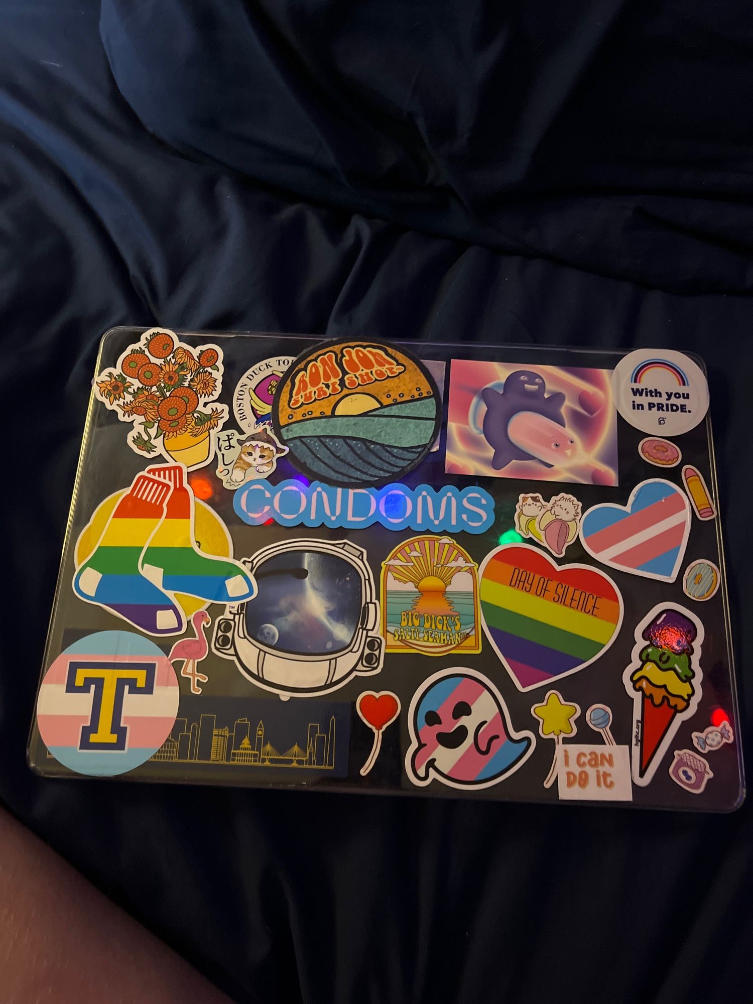 a mac laptop case covered in stickers, most are pride related