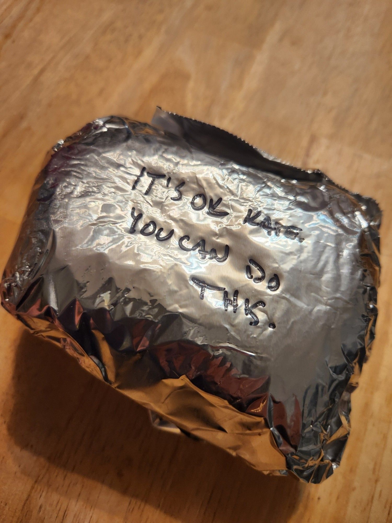 Sandwich wrapped in foil. Sharpie text says "it's OK Kate you can do this"