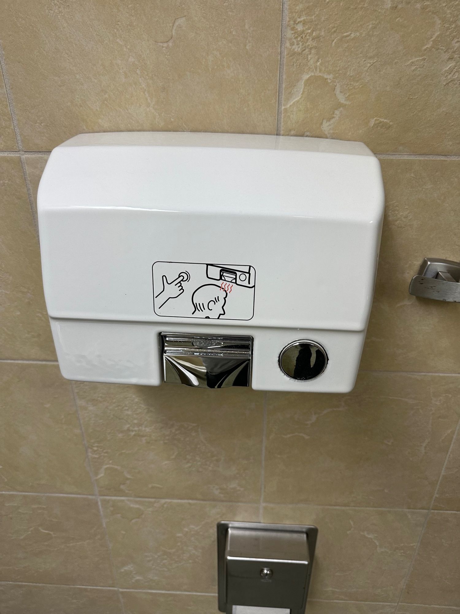 A sign on a bathroom dryer of a man using the device to blow hot air on his bald pate. (I think?)