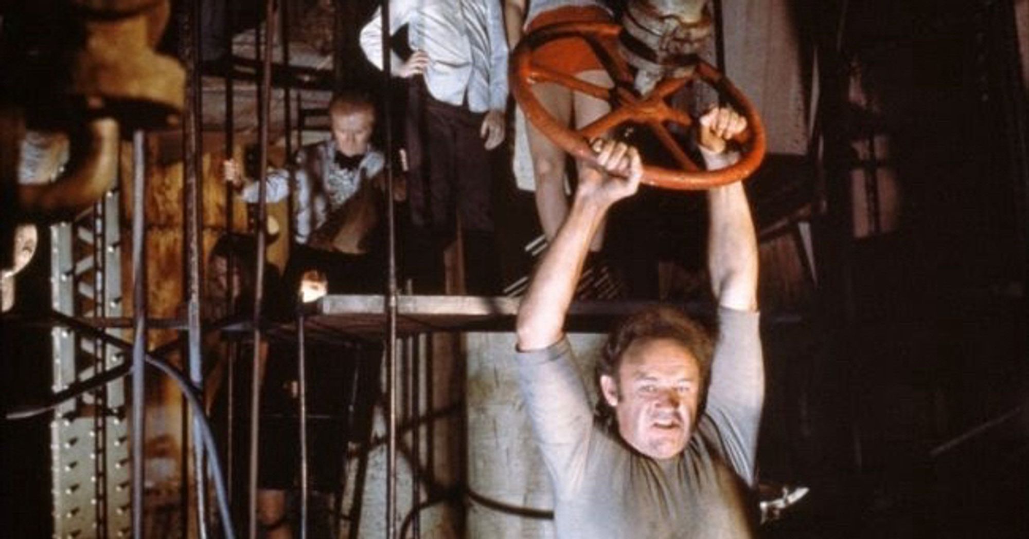 Gene Hackman in the Poseidon Adventure hanging off a red valve wheel in an iconic scene.