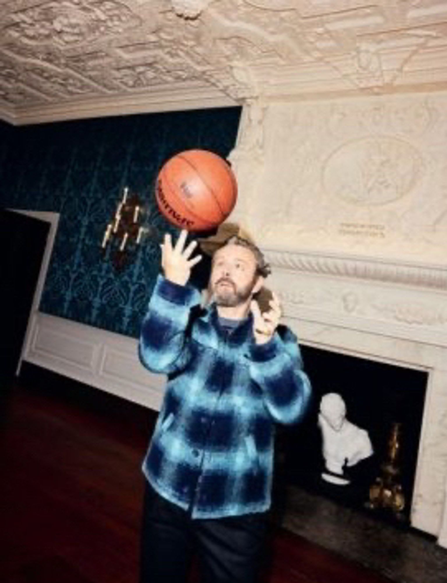 Michael Sheen playing with a basketball inside a living room