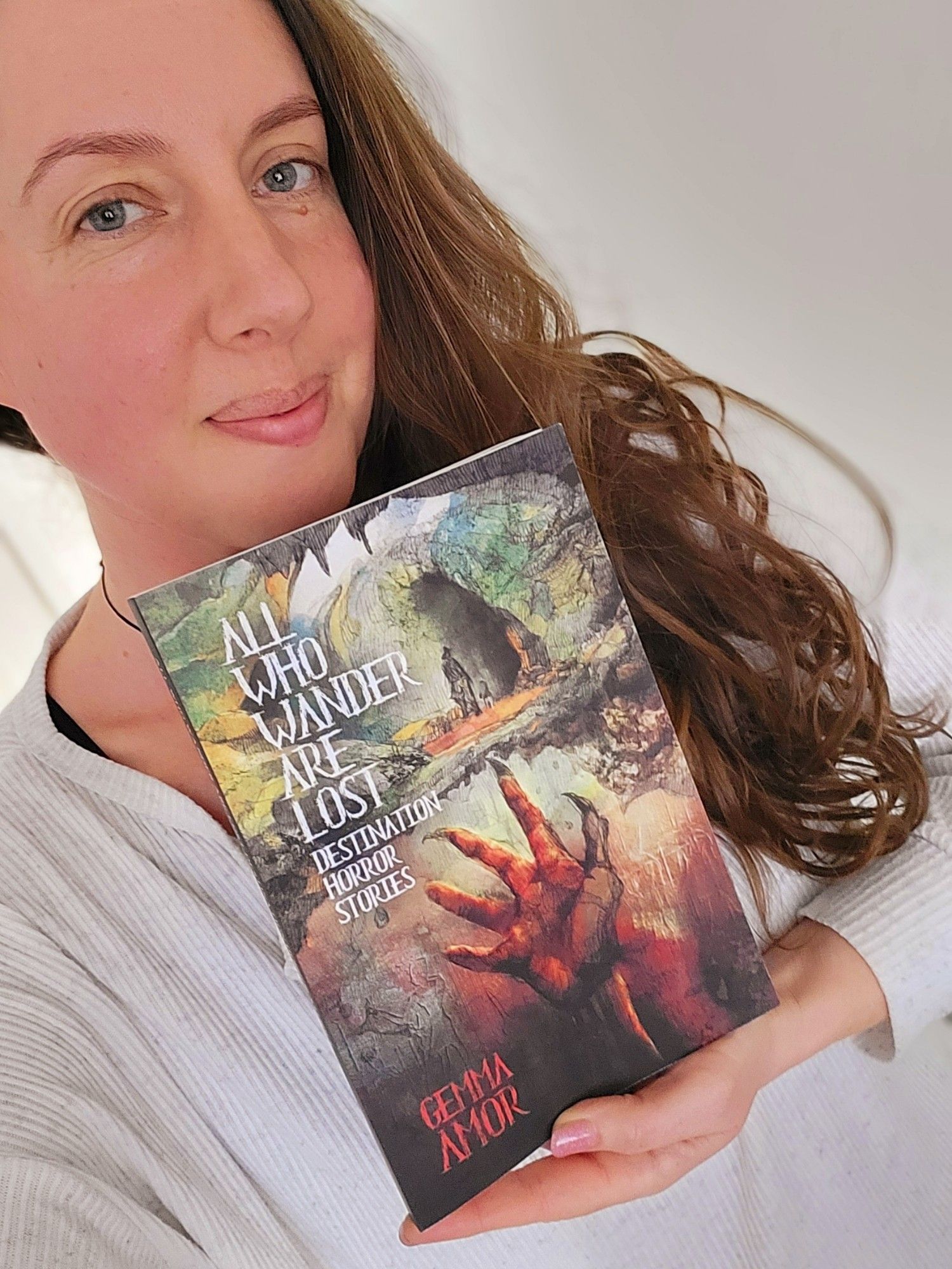 Gemma Amor posing with her new collection of travel themed short horror stories ALL WHO WANDER ARE LOST