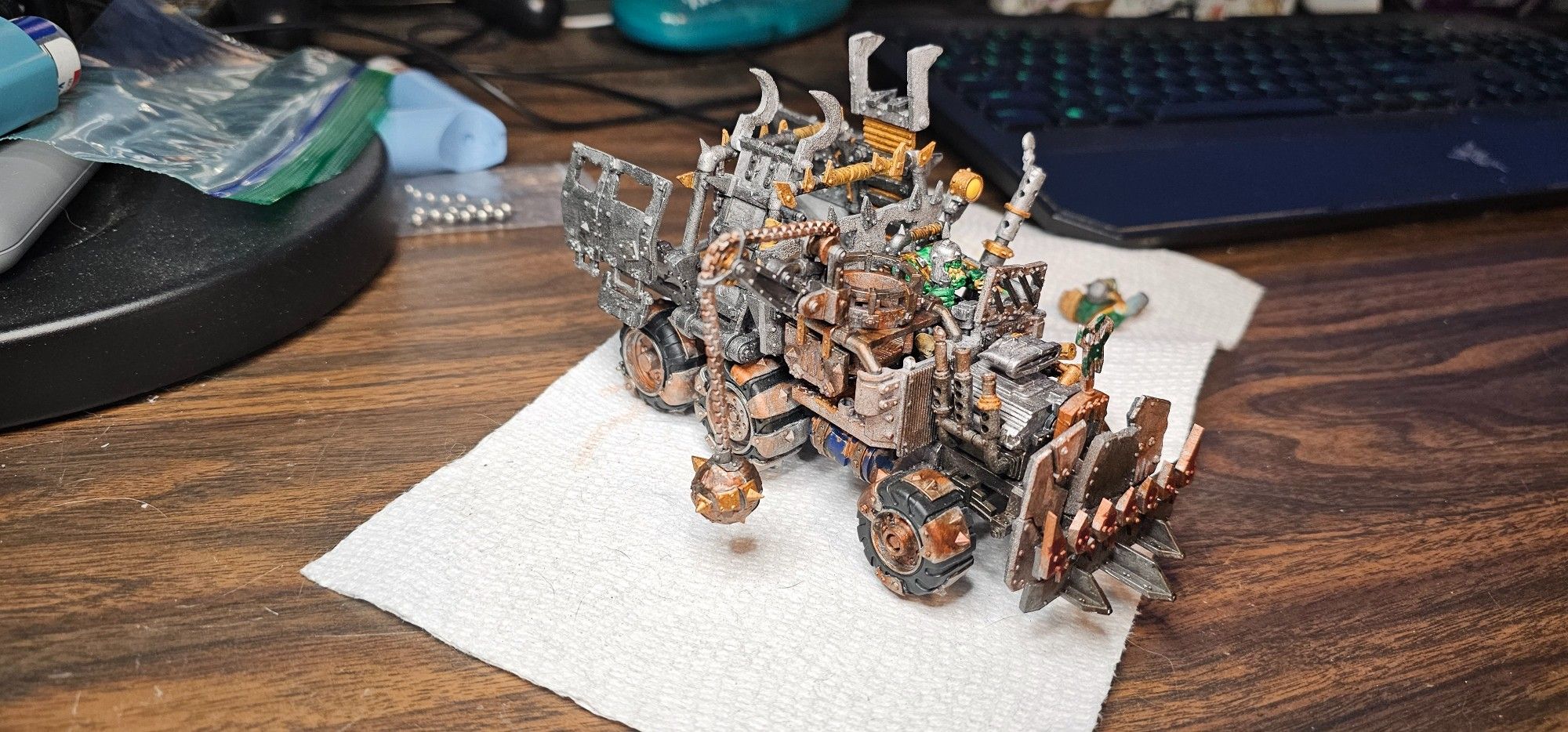 Warhammer 40k Ork Trukk oblique passenger side. Brown built up over orange on front wheels, and rust and muck built up on the cabin front. Drilled out engine exhaust has brown grime built up on it.