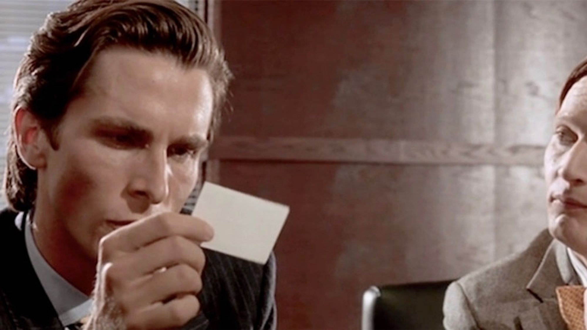 Patrick Bateman sweating holding a card