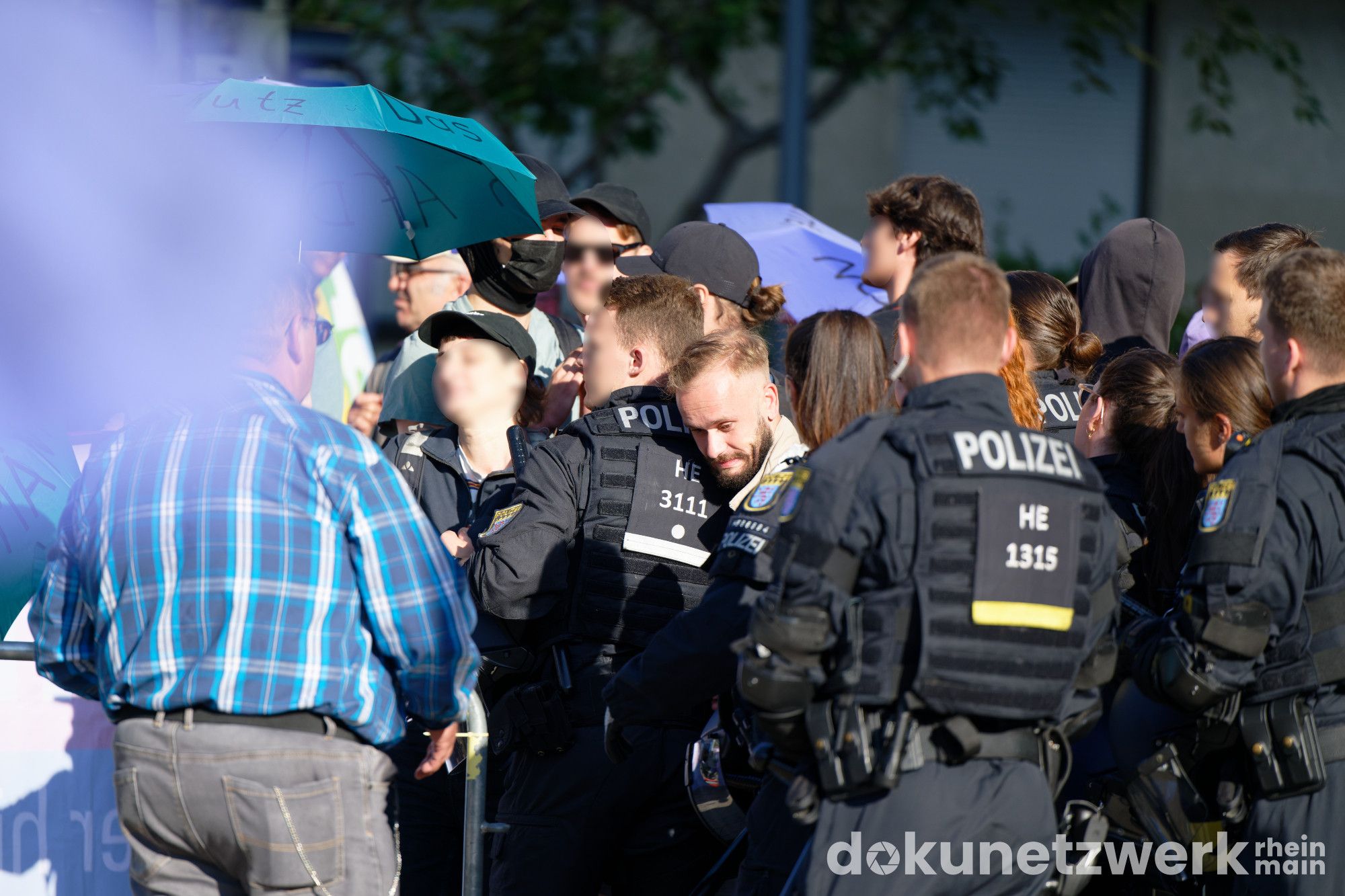 Gerangel zwischen Gegenprotest und Polizei. Zwischen zwei Polizisten drückt sich ein AfD-Nazi durch, um auf das Gelände der Stadthalle zu kommen