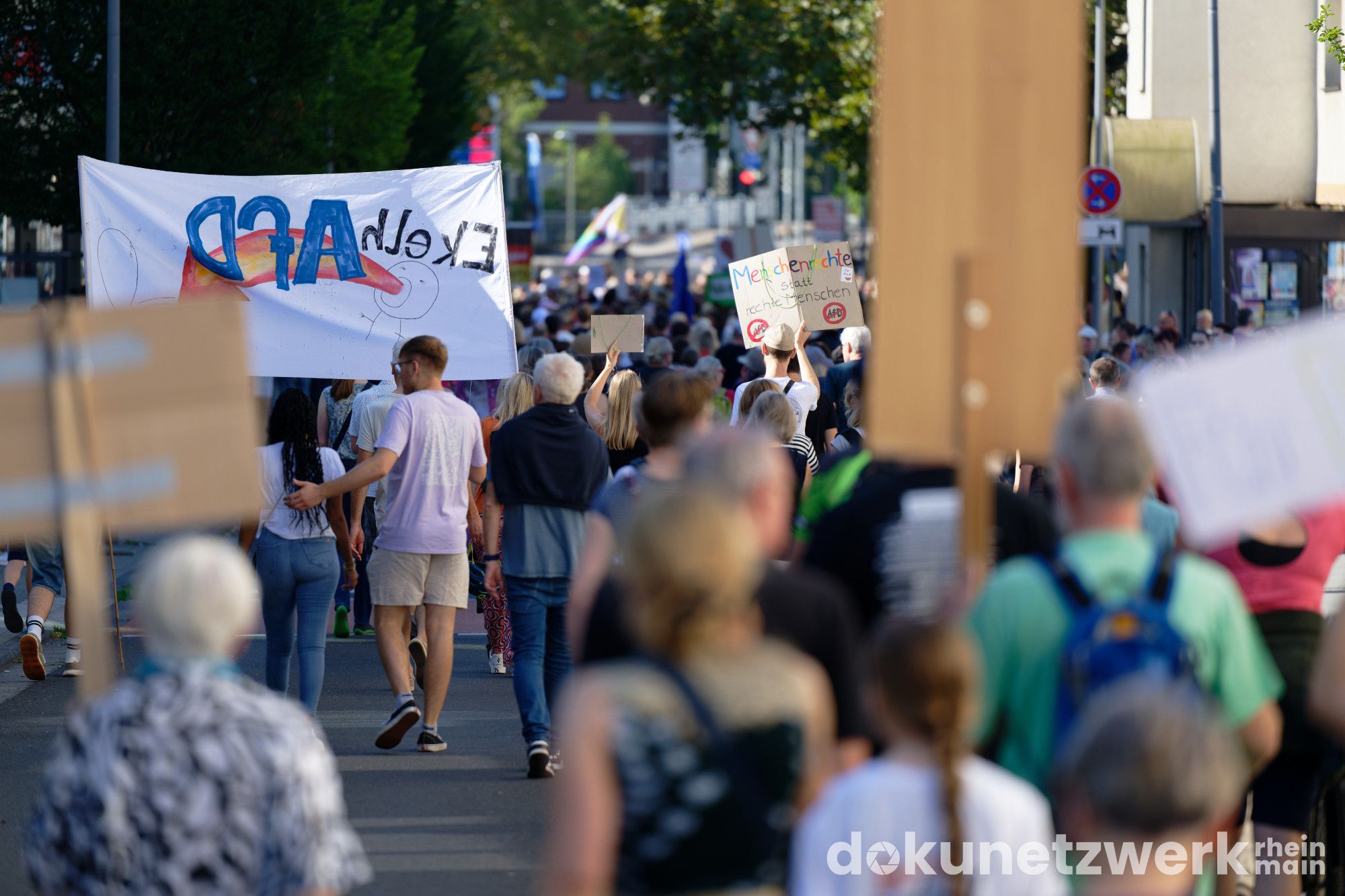 Ein Teil der Demo von hinten. Zu sehen sind viele verschiedene Menschen. Ein Hochtransparent mit der Aufschrift "Ekelhafd". Außerdem eine Pappe mit der Aufschrift in bunten Buchstaben "Menschenrechte statt rechte Menschen"