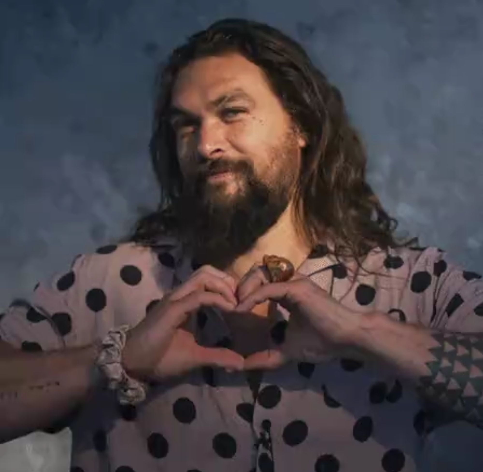 Jason Momoa qui fait un coeur avec les doigts car il a de la compassion pour quelqu'un qui a visiblement si peu de goût