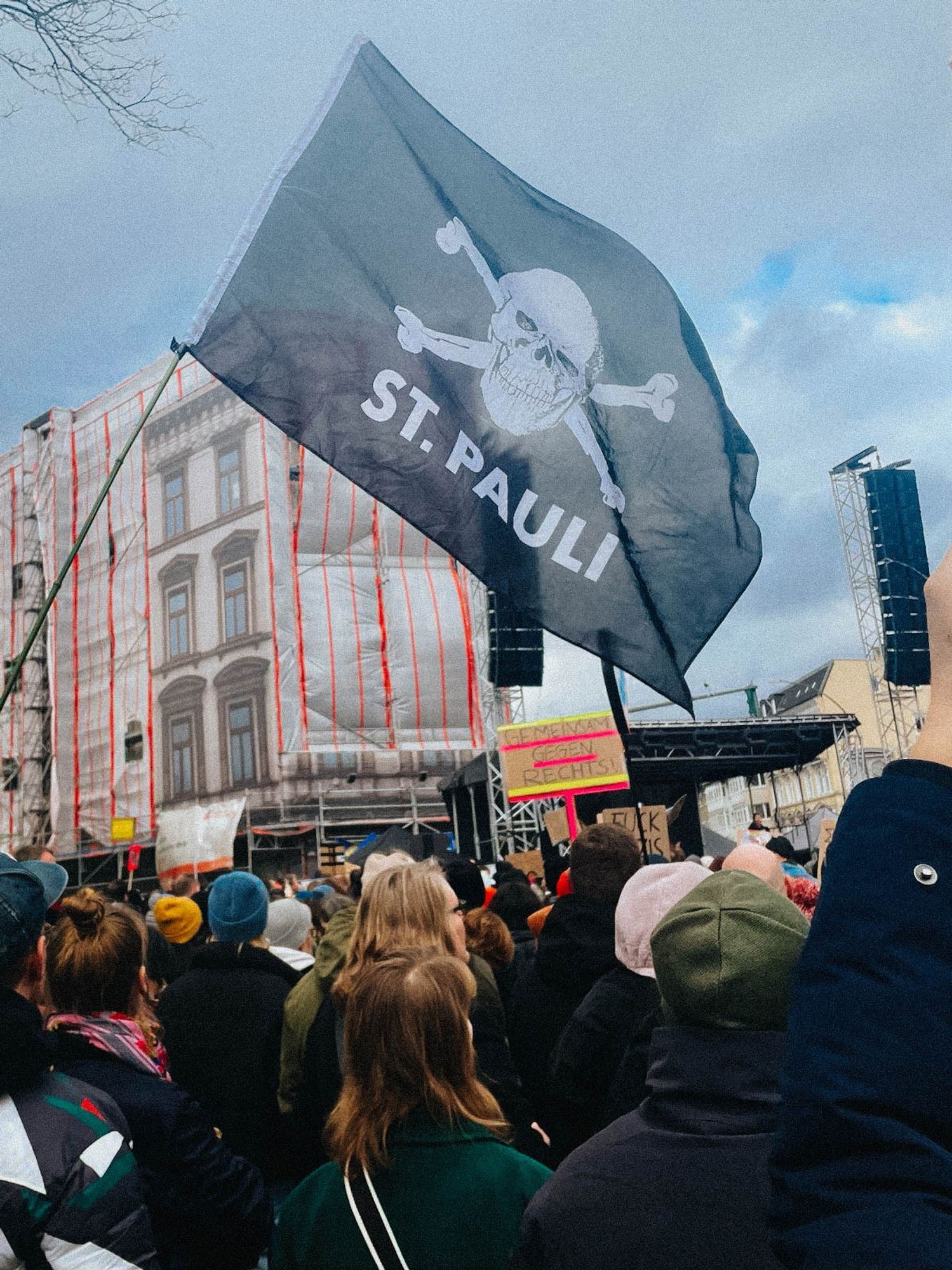 Eine  Totenkopffahne des FC St. Pauli weht über Demonstrant*innen.