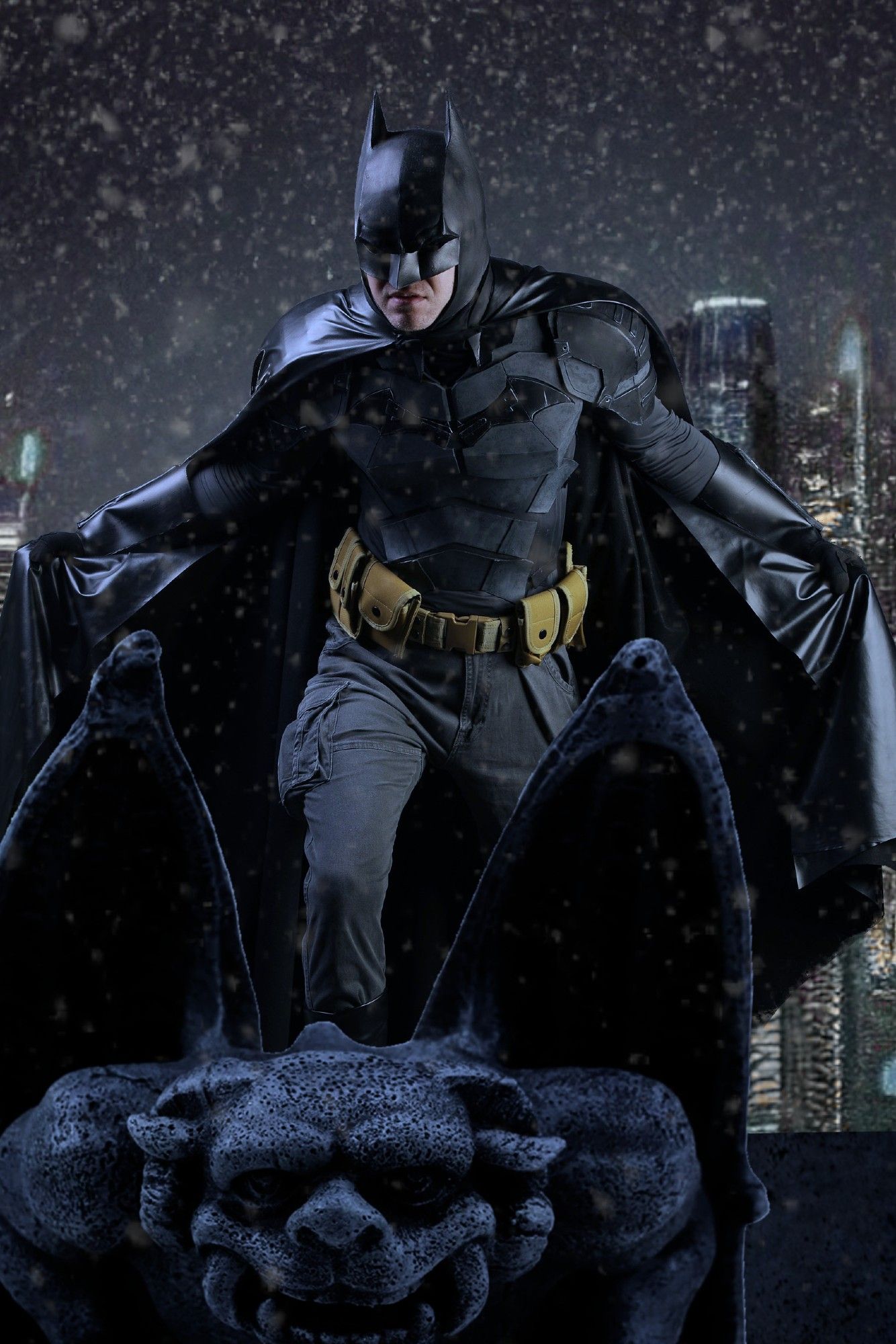 Cosplayer in a selfmade Batsuit edited to be standing on a gargoyle during a snowy winter night.