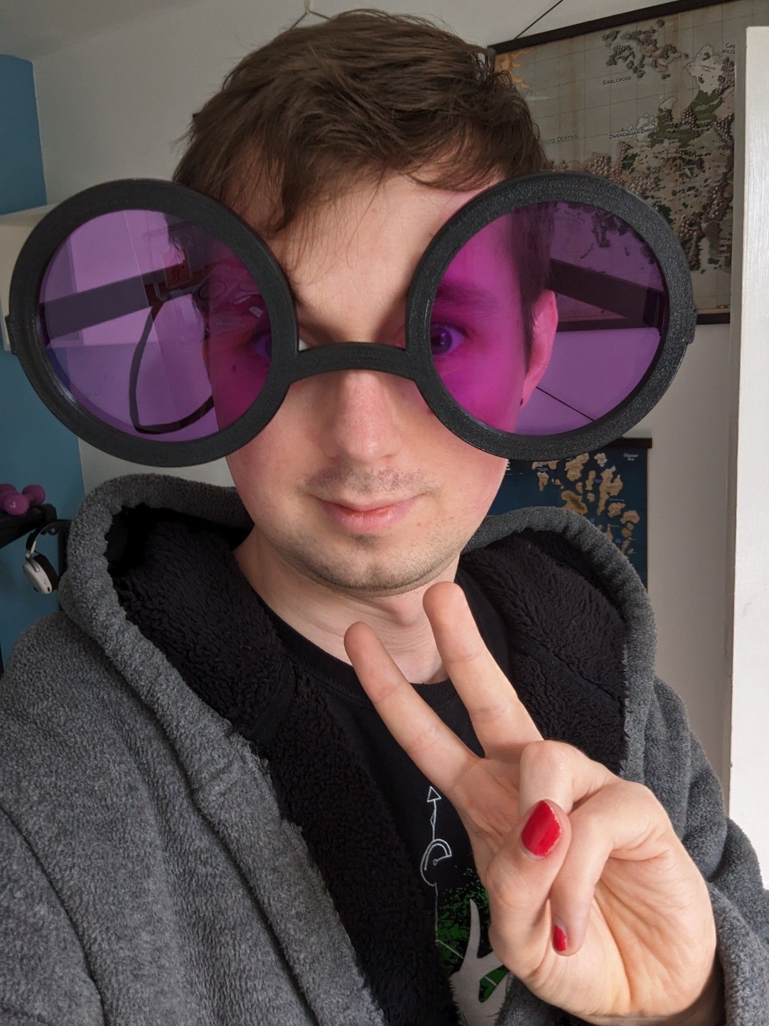 The black circular frames, with purple lenses attached, worn by myself to show how comically sized they are. I'm doing the peace sign with my left hand because I am kawaii