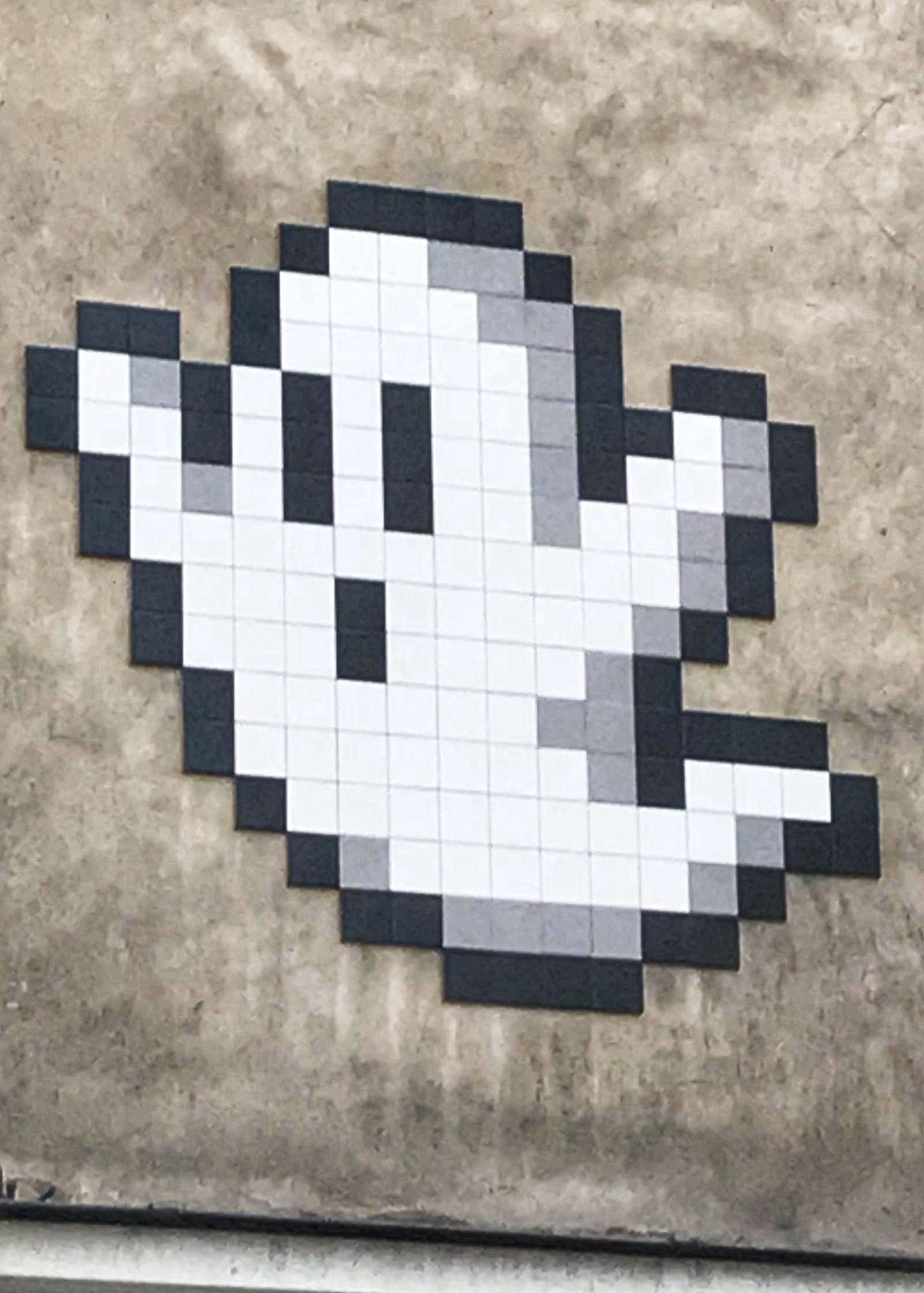 Invader tiled ghost on the side of a building.