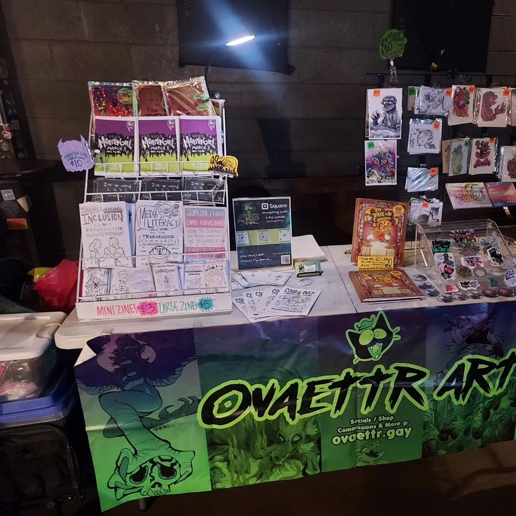 My vendor setup for Ovaettr Art with banner, zines, stickers prints and buttons