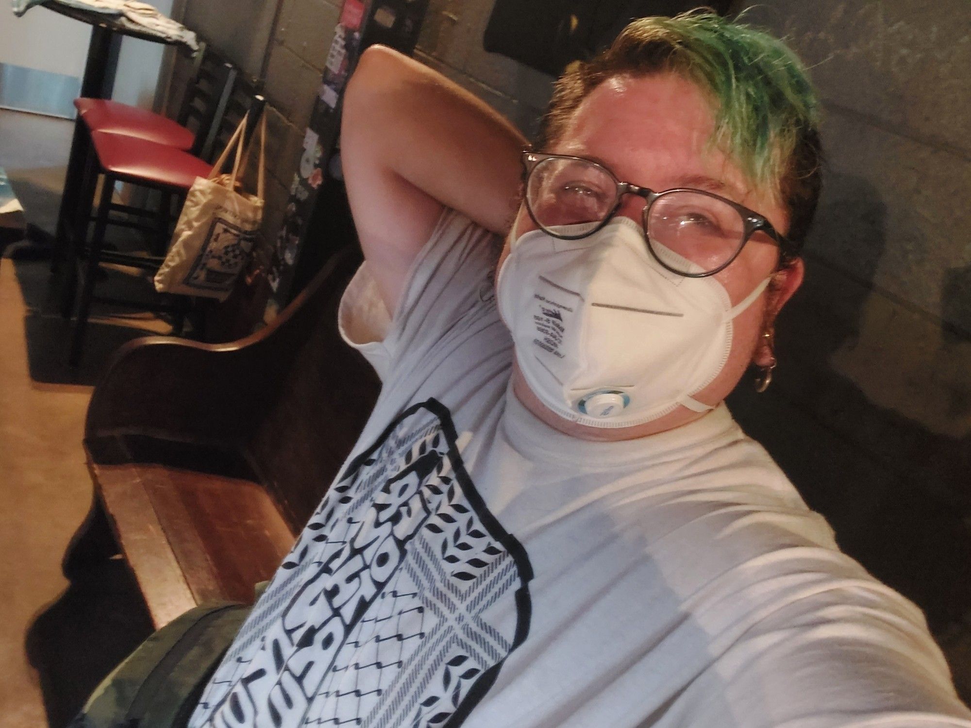 Me smiling with my white Free Palestine shirt and green hair. I have an n95 mask on thats white.