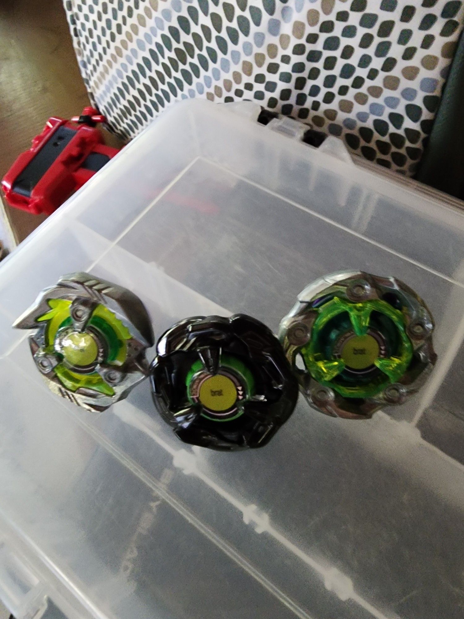 3 green and black beyblades with the Charlie xcx brat logo as a sticker