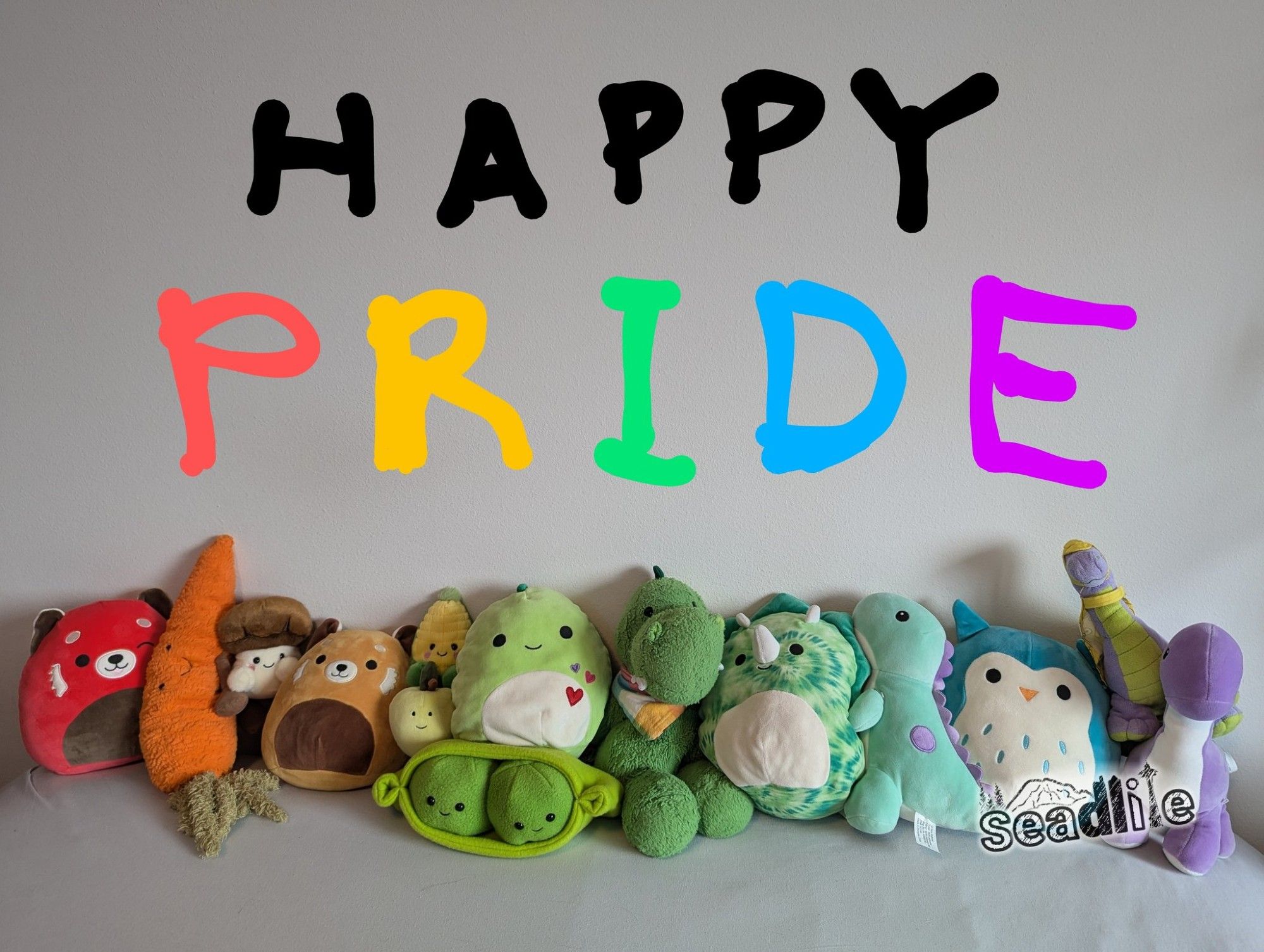 A row of colorful plushies, sorted in rainbow order from red to purple. Text above says "HAPPY PRIDE"