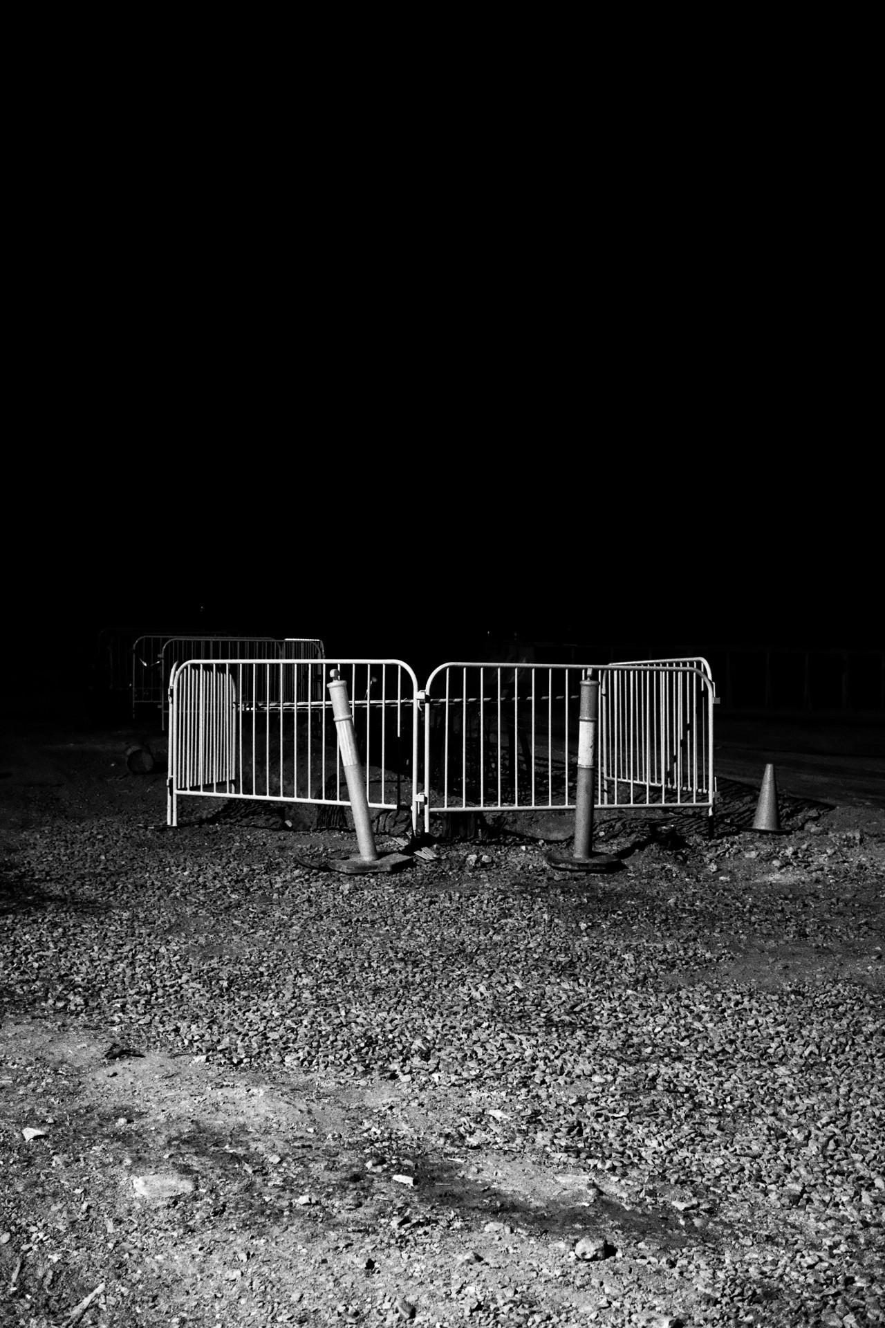 A few metal gates lay in the center of frame along with lots of gravel dirt & rocks.
The sky is pitch black fading into darkness as if it is the abyss.
It is night