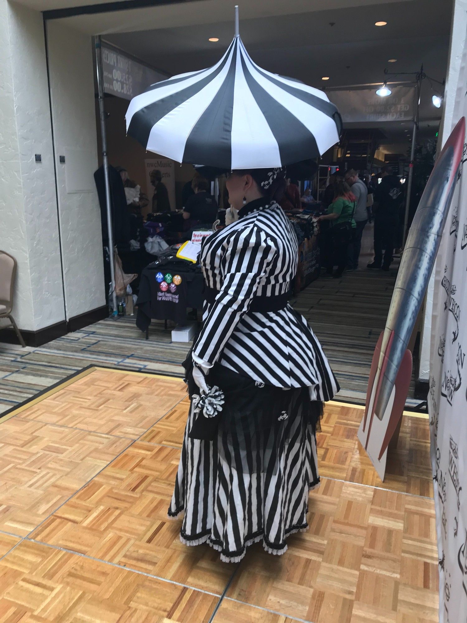 A side view of me in the outfit described in the previous photos, with the parasol open and a black and white flower visible on my black handbag.