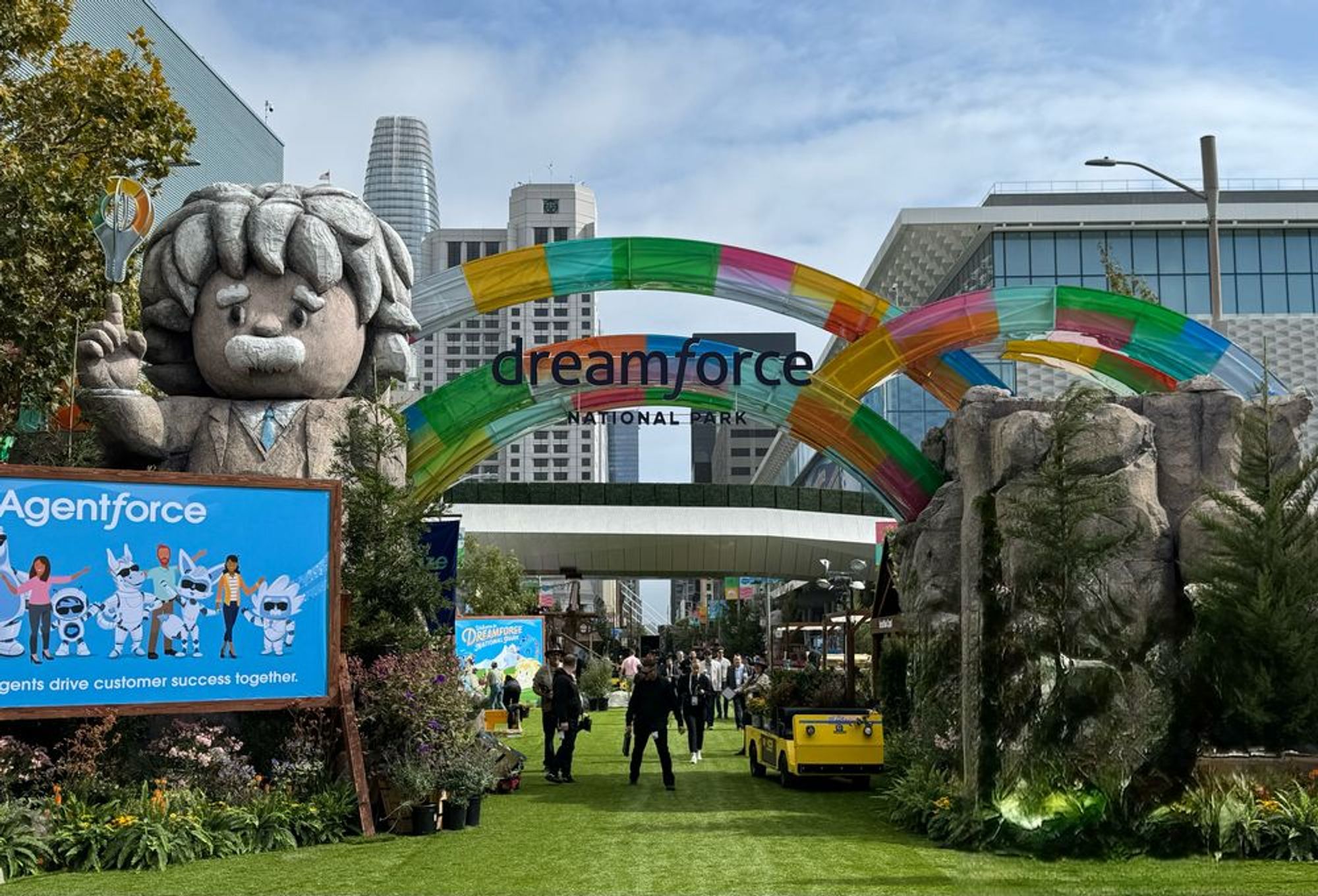 The entrance to Dreamforce looks like an amusement park entrance! Mascots and bright lights form an archway over a cartoon like forest path.