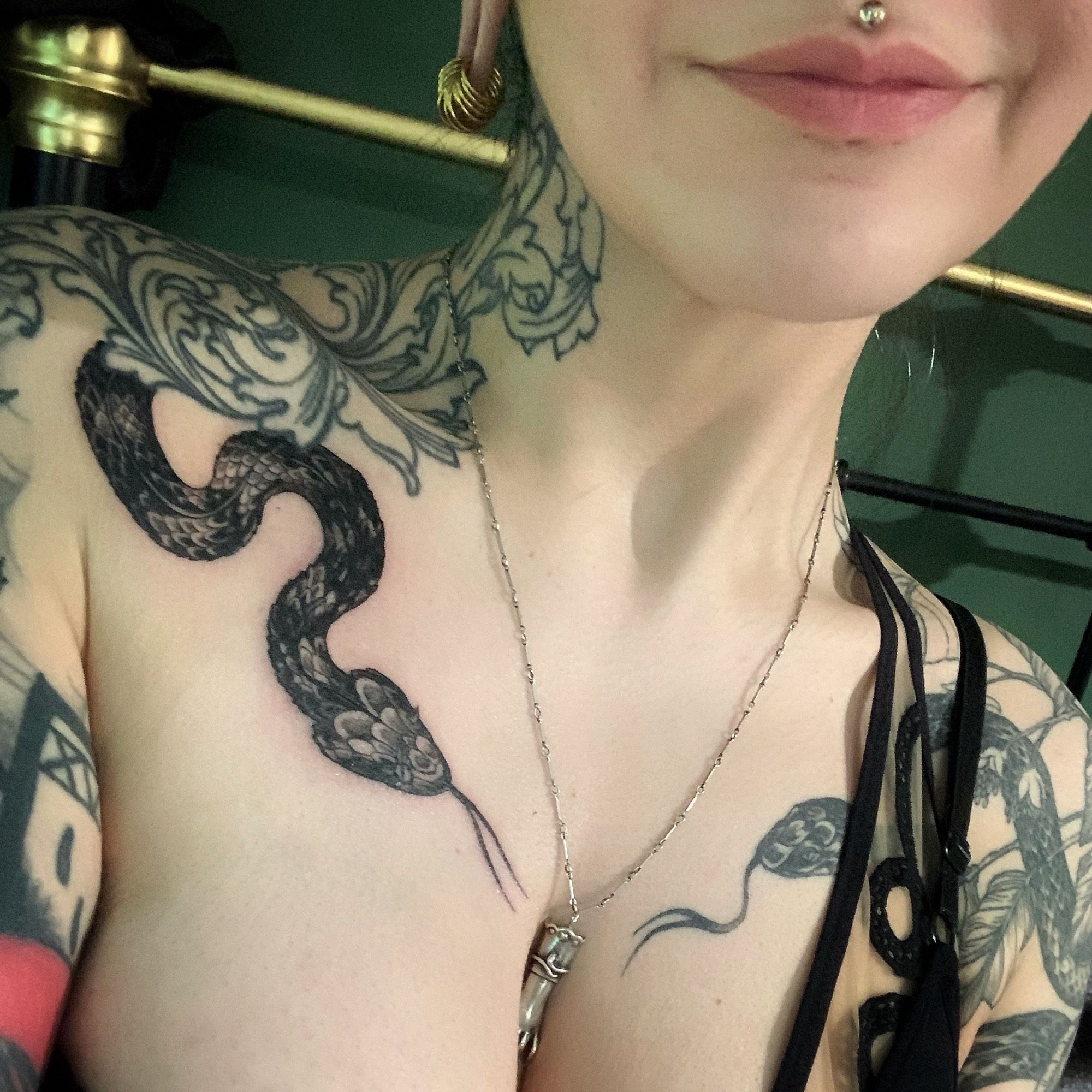 Close shot of my freshly tattooed décolletage area showing a newly done spider tailed horned viper amongst my healed arm, shoulder, chest & neck tattoos.