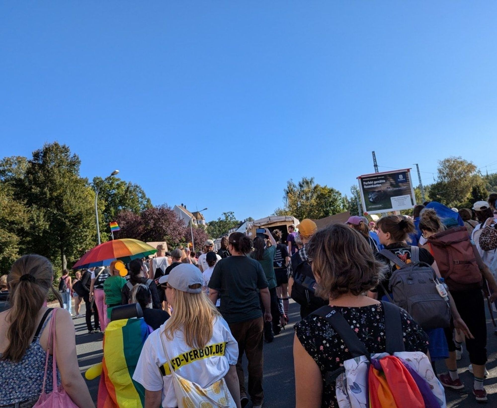 Bild vom CSD in Döbeln. Viele Menschen mit Regenbogenflaggen und Transparenten, im Hintergrund ein Lautsprecherwagen