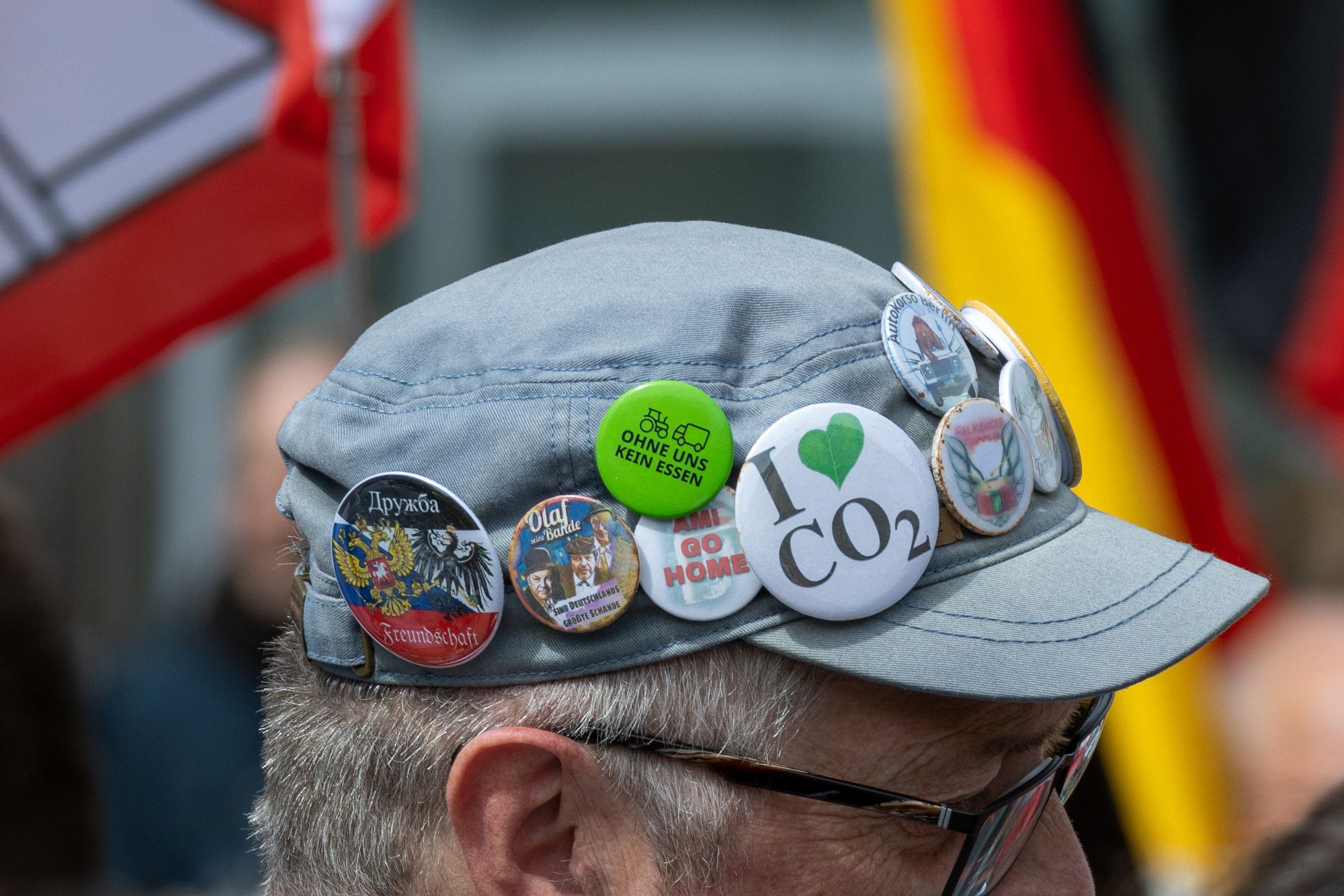 Viele politische Buttons an einer Cap; u.a. "I love CO2" oder "Freundschaft mit Russland"