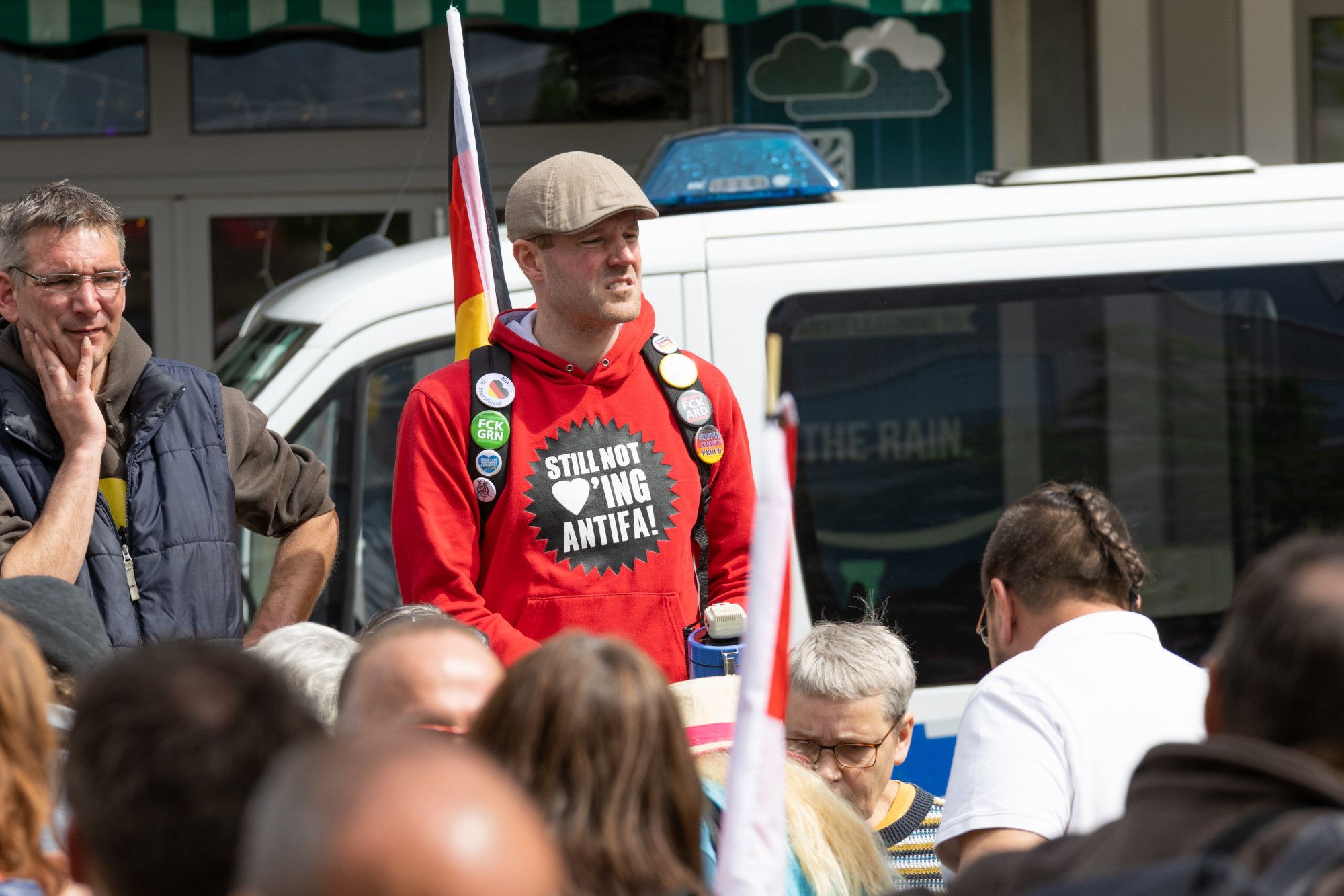 Ein Mann mit vielen Buttons und einem roten"Still not loving Antifa" Pullover