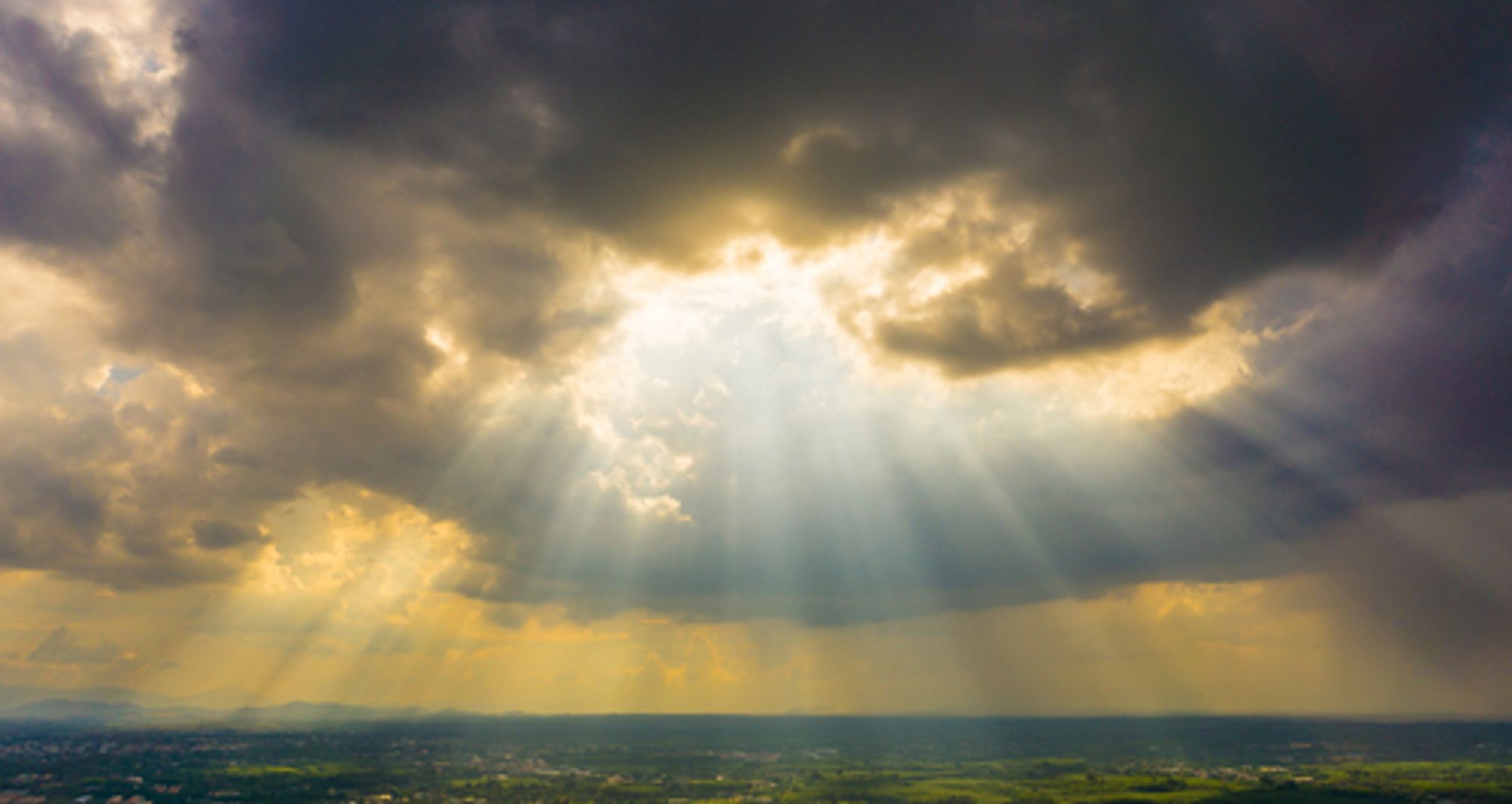 A photograph of the sun shining through clouds.