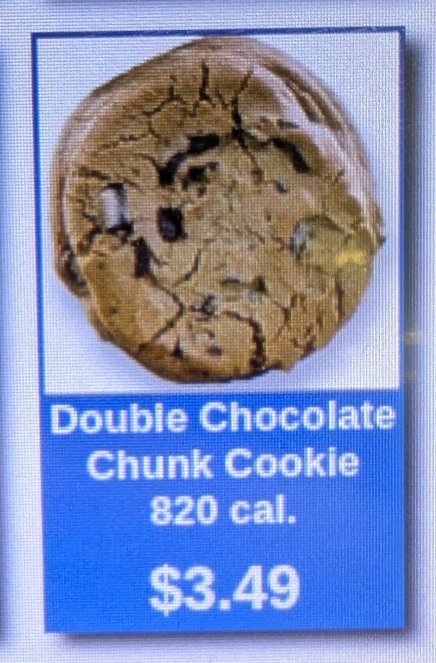 Pic of cookie item on video display, showing a $3.49 chocolate chip cookie which is EIGHT HUNDRED AND TWENTY CALORIES!