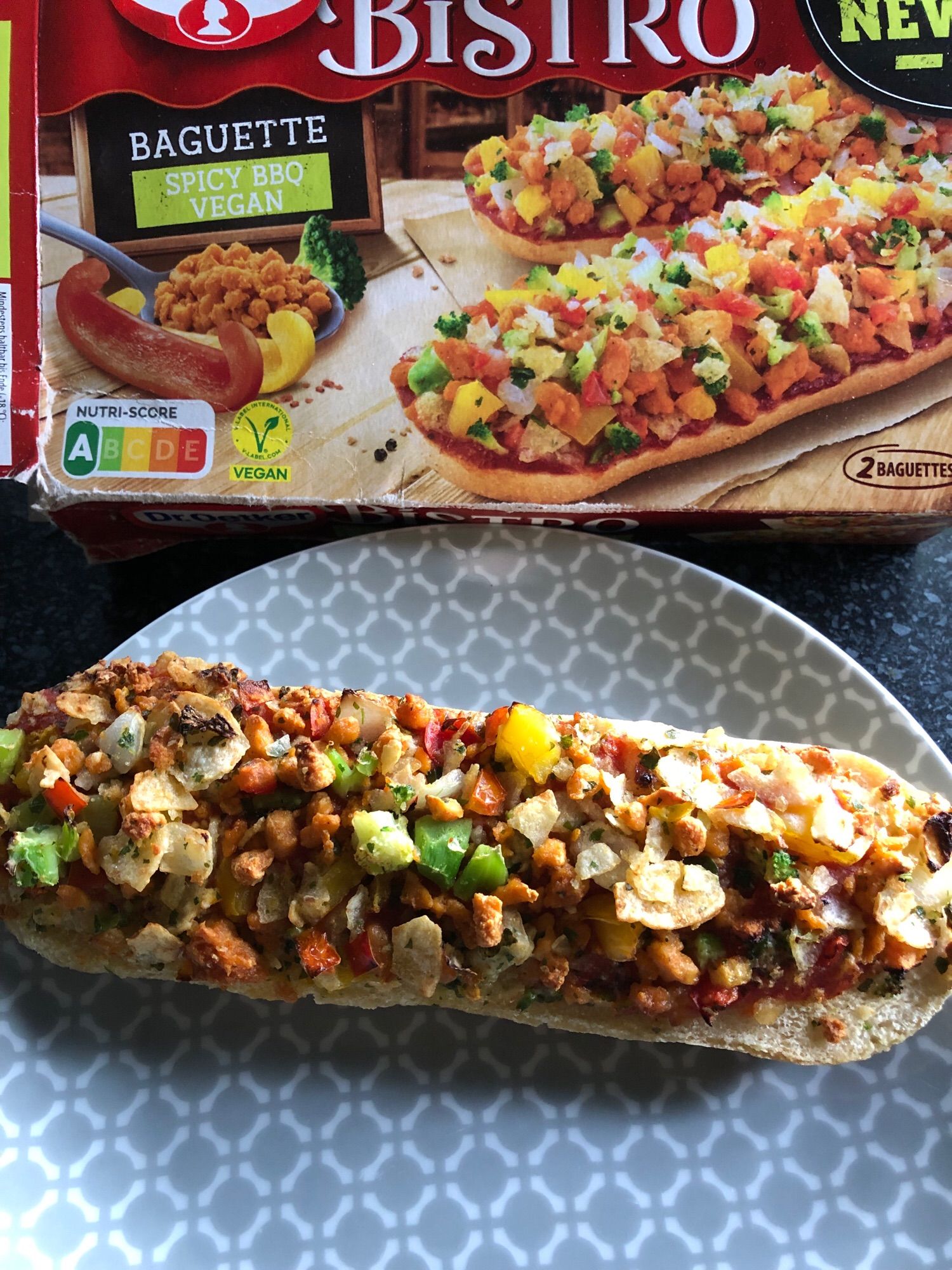 Oben die Verpackung Veganes Bistro Baguette Barbecue, darunter auf einem Teller ein fertig gebackenes Baguette