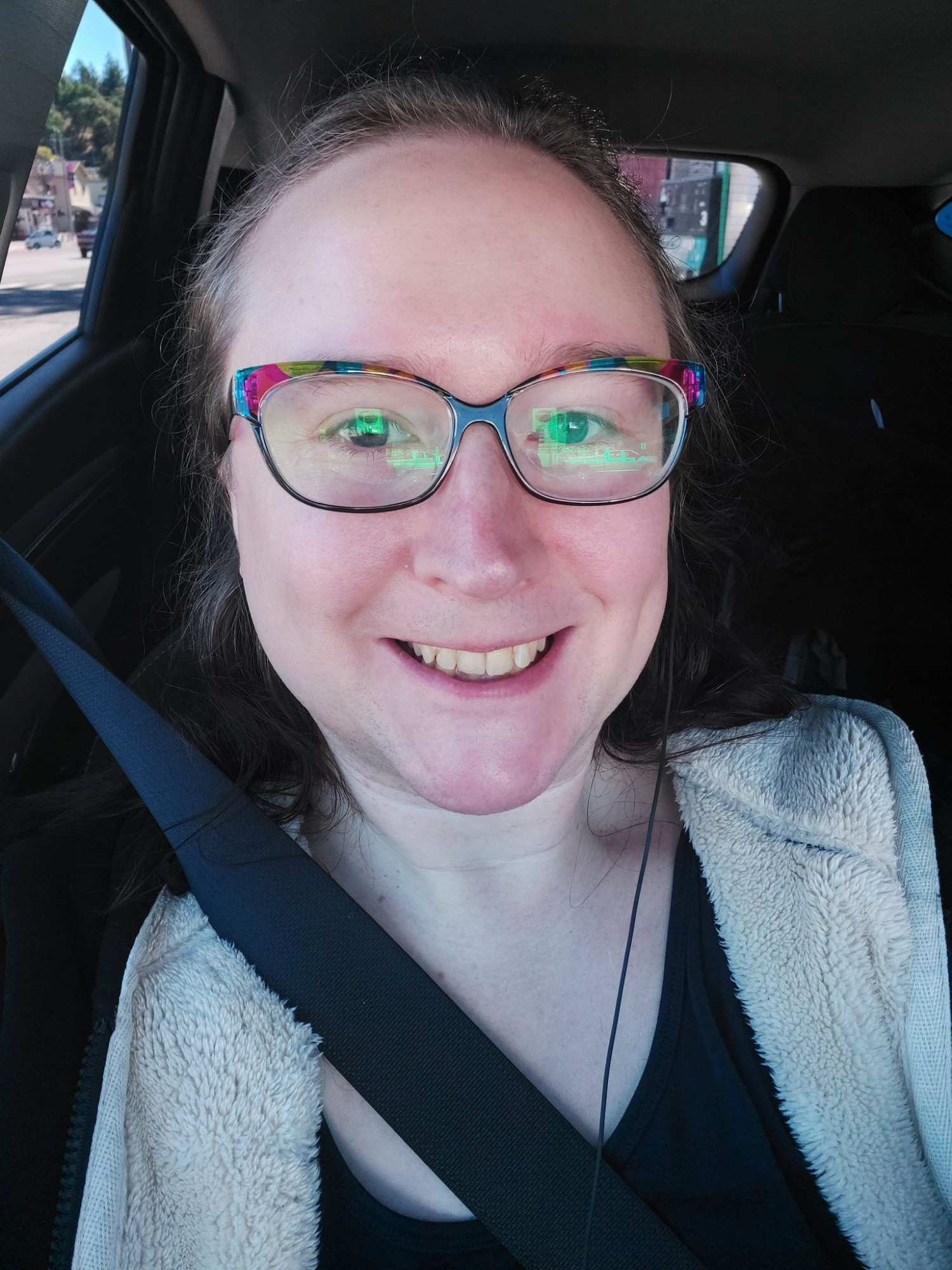 long black hair, smiling, black sweatshirt. in a car for some reason. white trans woman 