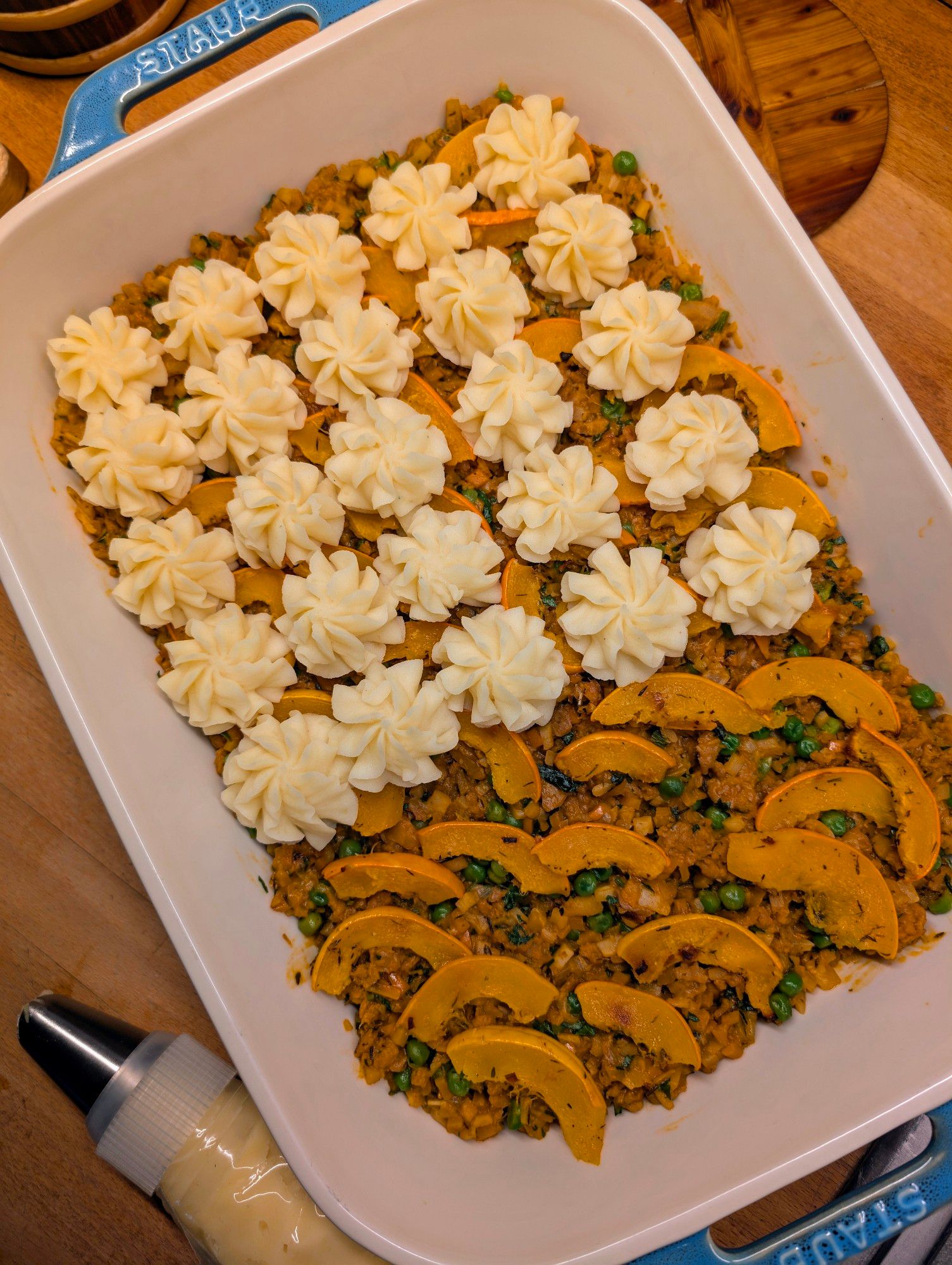 Shepherd's Pie in einer Auflaufform mit Püree Rösschen. Die Füllung besteht aus verschiedenen Gemüsesorten und Hokkaido Kürbis. Das Gericht ist vegan.