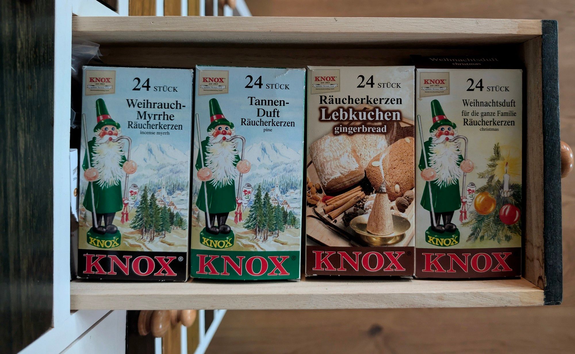 Vier Packungen verschiedener Sorten Weihnachtsduft der Marke Knox liegen nebeneinander in einer Schublade. Von oben fotografiert.